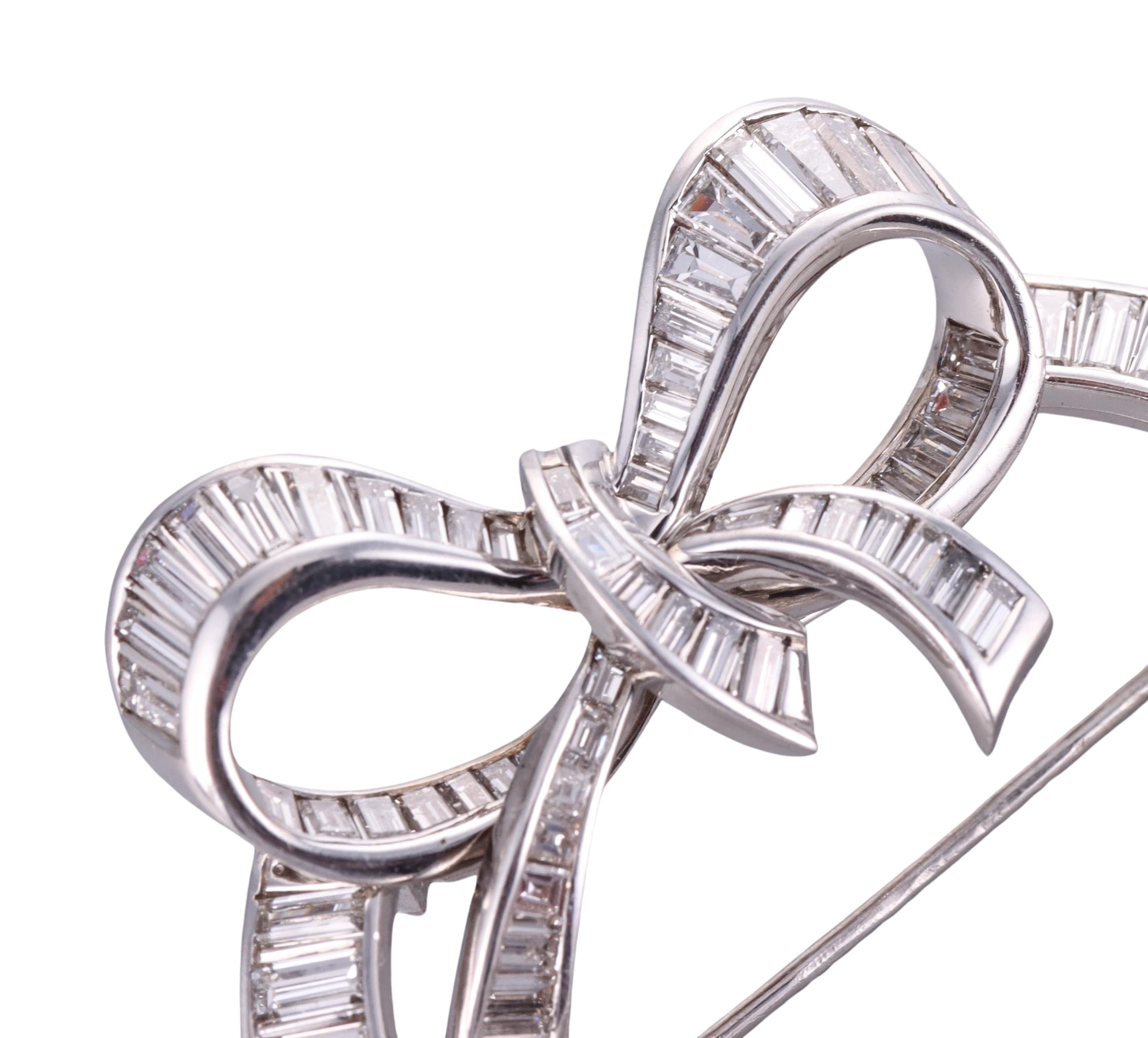 Classic platinum open circa and bow brooch, by Cartier, circa 1950s.  The brooch is set with approximately 5ctw in G/VS baguette diamonds. Measures 1.75