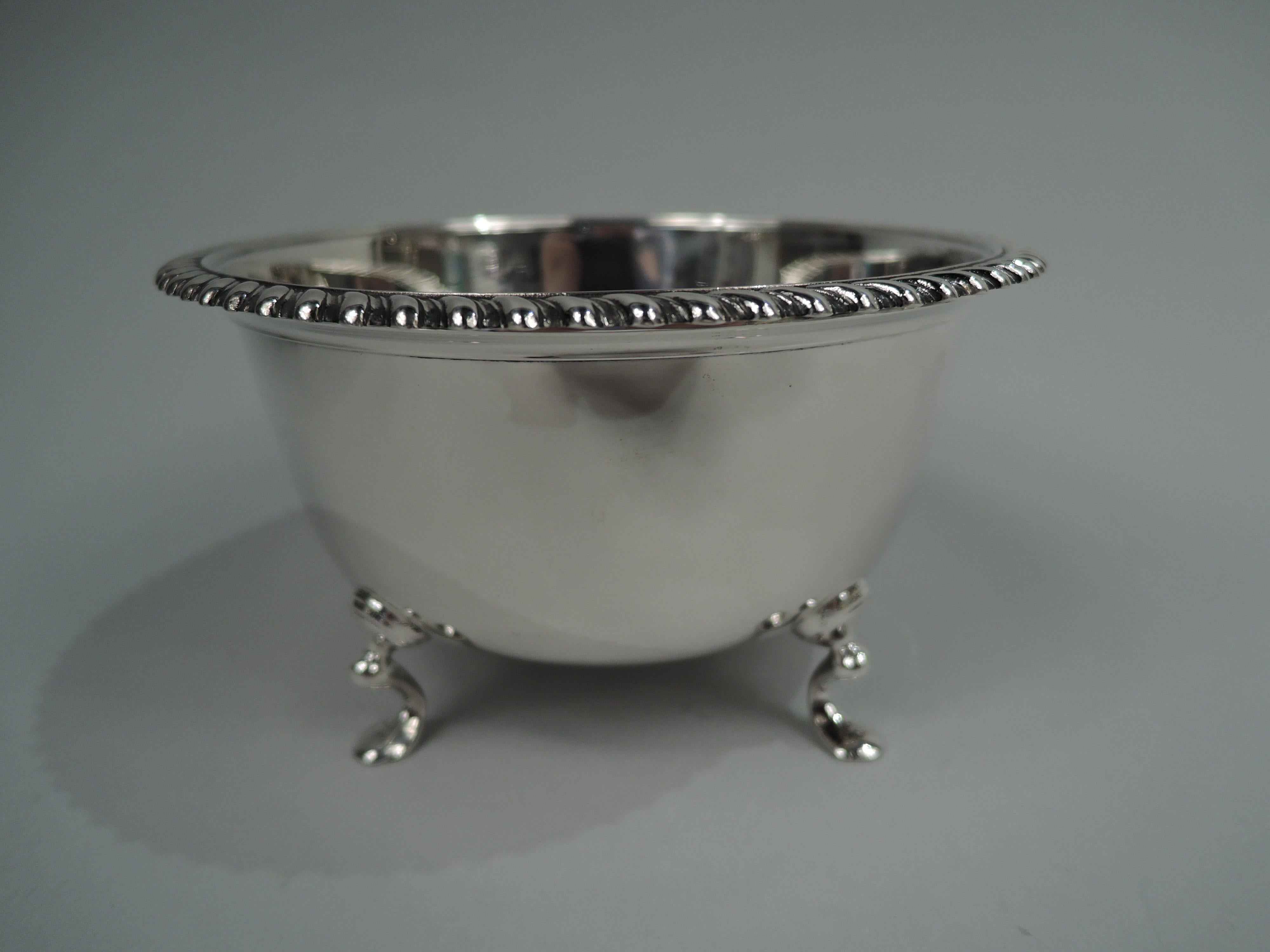 Modern American Georgian sterling silver bowl. Retailed by Cartier in New York. Tapering with curved bottom and flat gadrooned rim; four hoof supports. Fully marked including retailer’s stamp and no. 9576AB. Weight: 6.5 troy ounces.