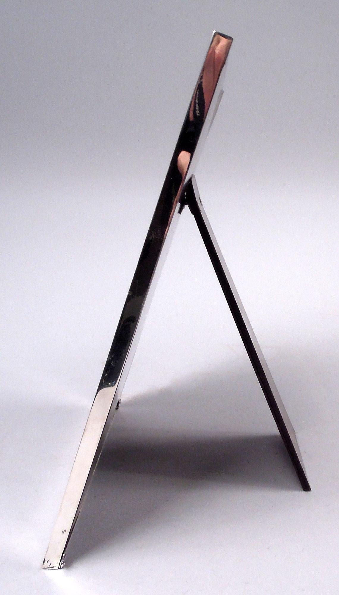 Marco de plata de ley americano de mediados de siglo. Vendida por Cartier en Nueva York. Ventana rectangular con marco plano liso. Con cristal, forro de seda y respaldo de laminado de madera y soporte de caballete abatible para exposición en