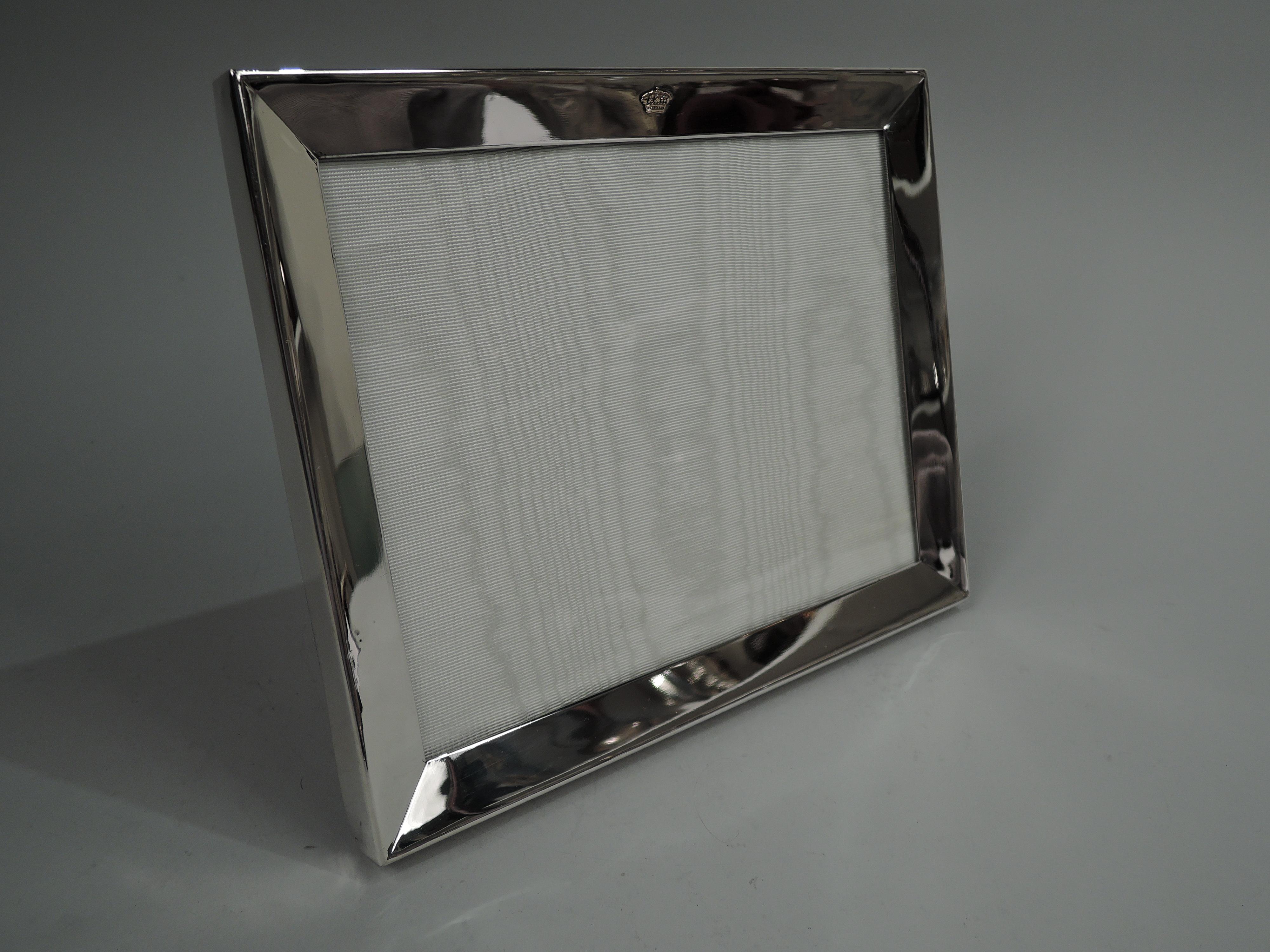 American Midcentury Modern sterling silver picture frame. Retailed by Cartier in New York. Rectangular window in same surround with convex front and flat sides. In hard-to-find landscape form with regal gold crown applied to top rail. With glass,