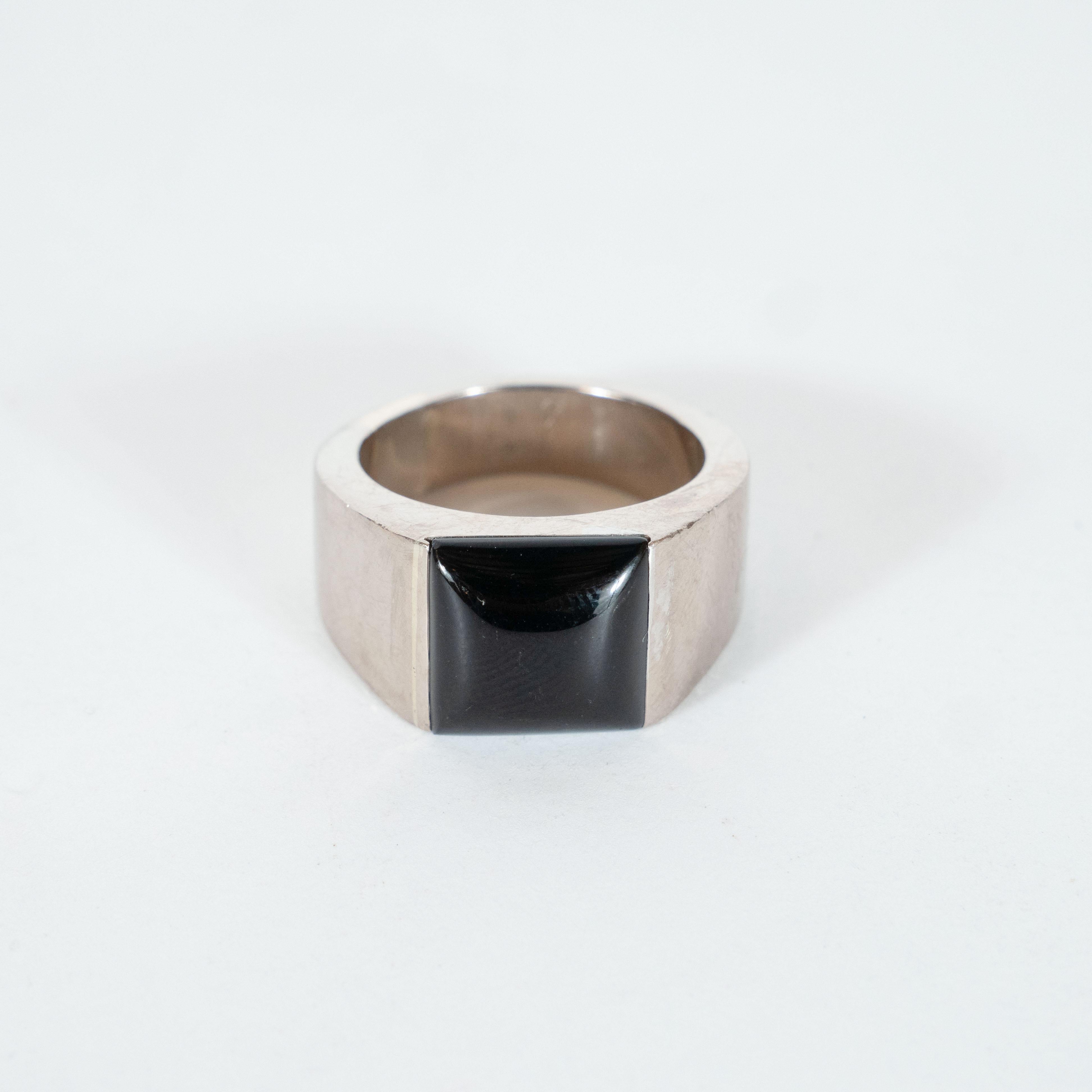 This elegant modernist ring was realized by Cartier- one of the world's finest purveyors of jewelry since its founding in 1847- in France. It features a 18kt white gold body fitted a concave square black onyx. With its neutral palate, impeccable