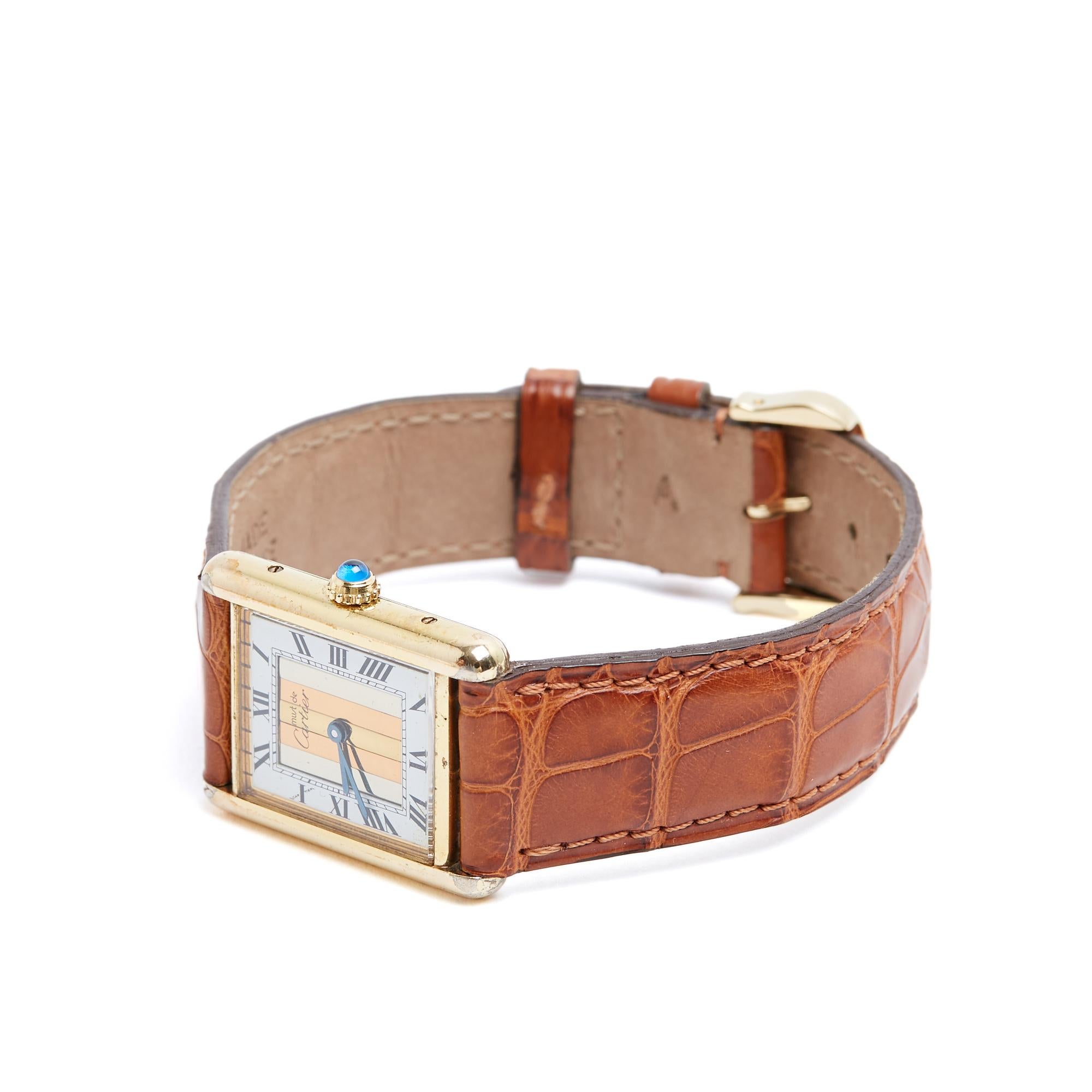 Cartier Must Tank model watch in vermeil (925/1000 gold-plated silver), white background with Roman numerals inlaid with a tricolor metal motif, dedicated to the Trinity series, quartz, camel leather strap and Cartier gold-plated metal pin buckle.