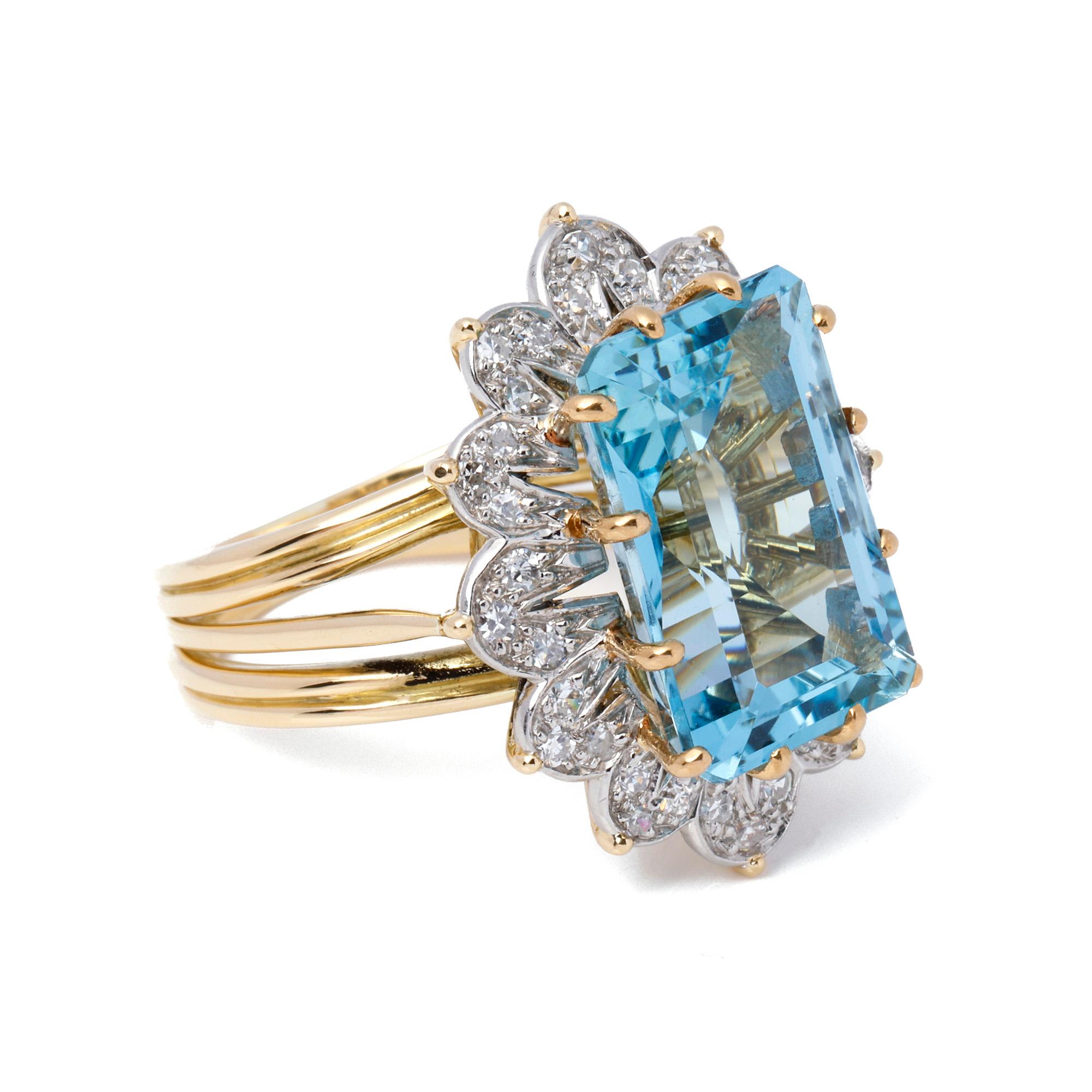 This ring, signed Mtd Cartier, features a central emerald cut aquamarine stone measuring approximately 16.45mm x 10.75mm surrounded by 36 single cut diamonds within a bi colour ring setting. UK ring size O. EU ring size 55. US ring size 7 1/4.