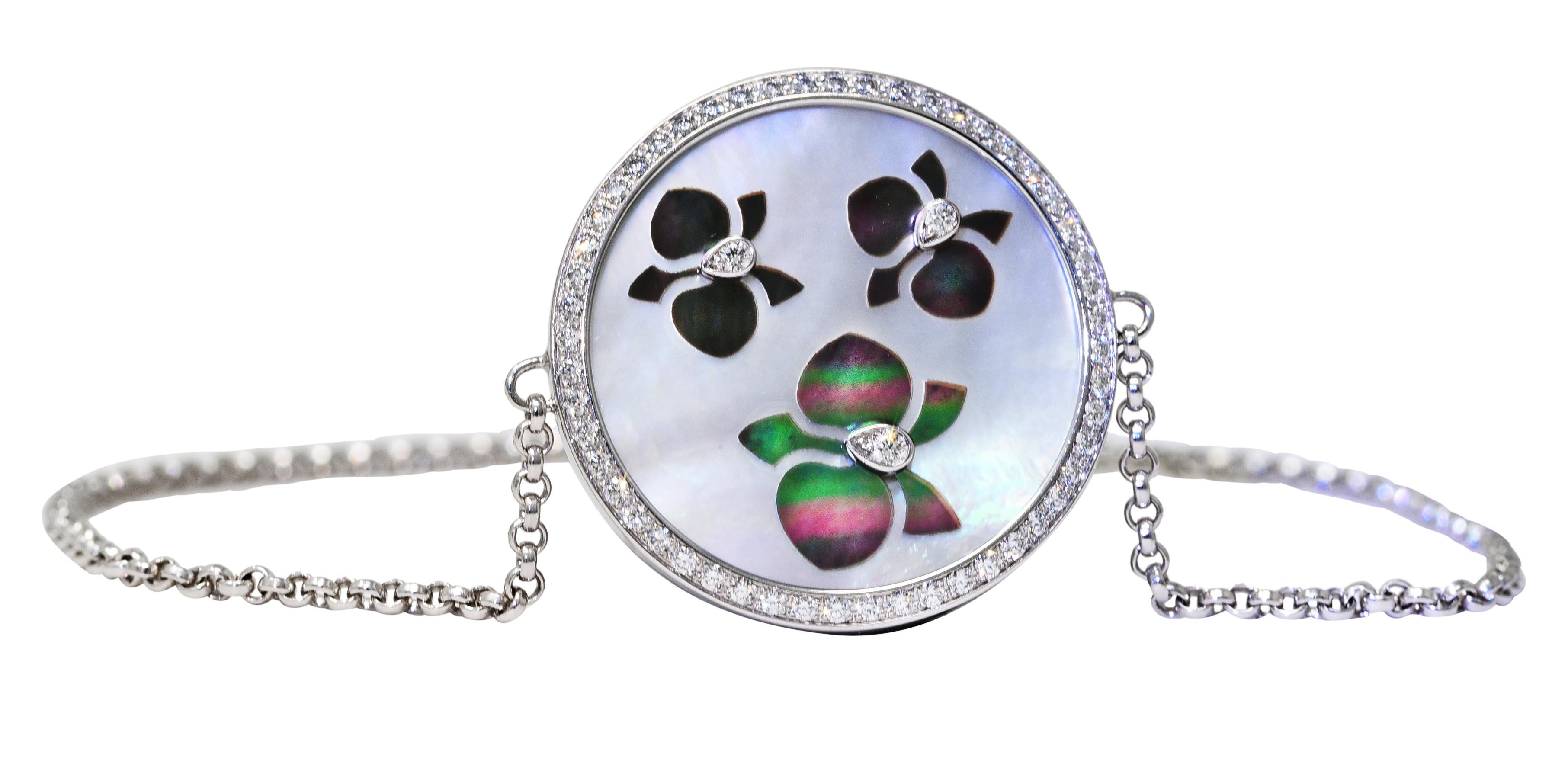Comprised of cable chain centering a round disk shaped station with a tablet of mother-of-pearl. Measuring 18.5 mm round - opaque white in body color with strong spectral iridescence. Featuring an inlaid orchid motif of mother of pearl - gray in