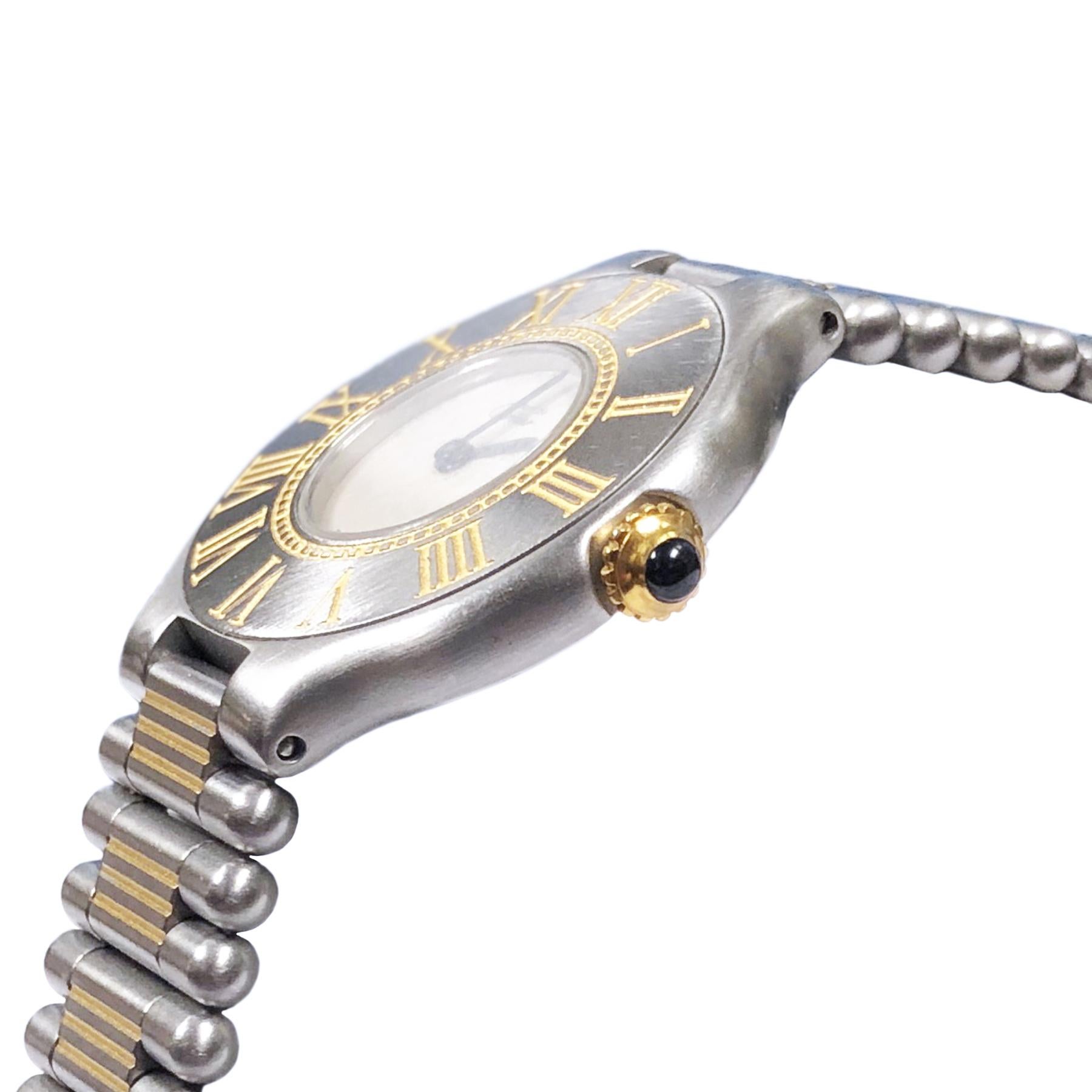 Circa 1990s Cartier, Must De Cartier 21 Ladies Wrist watch, 28 MM Stainless Steel with Gold accents case and a Gold crown set with a sapphire. Quartz Movement, Silver Dial. 5/8 inch wide Steel and Gold link bracelet with Deployment clasp. Total