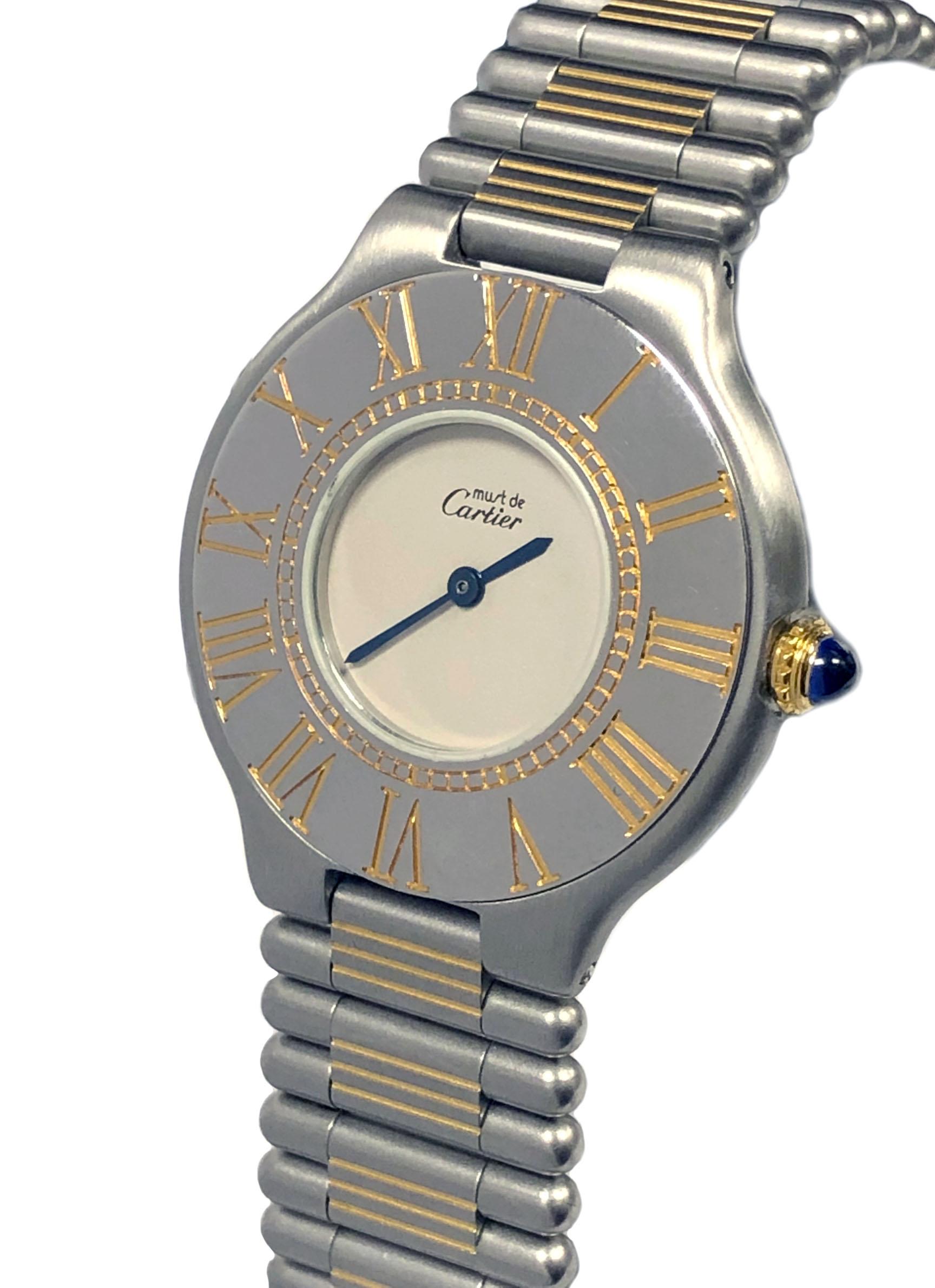 Circa 1990 Cartier, Must De Cartier 21 Mid Size Wrist watch, 31 M.M Stainless Steel  2 piece case with Gold accents and a Gold crown set with a sapphire. Quartz Movement, white Dial. 5/8 inch wide Steel and Gold link bracelet with Deployment fold