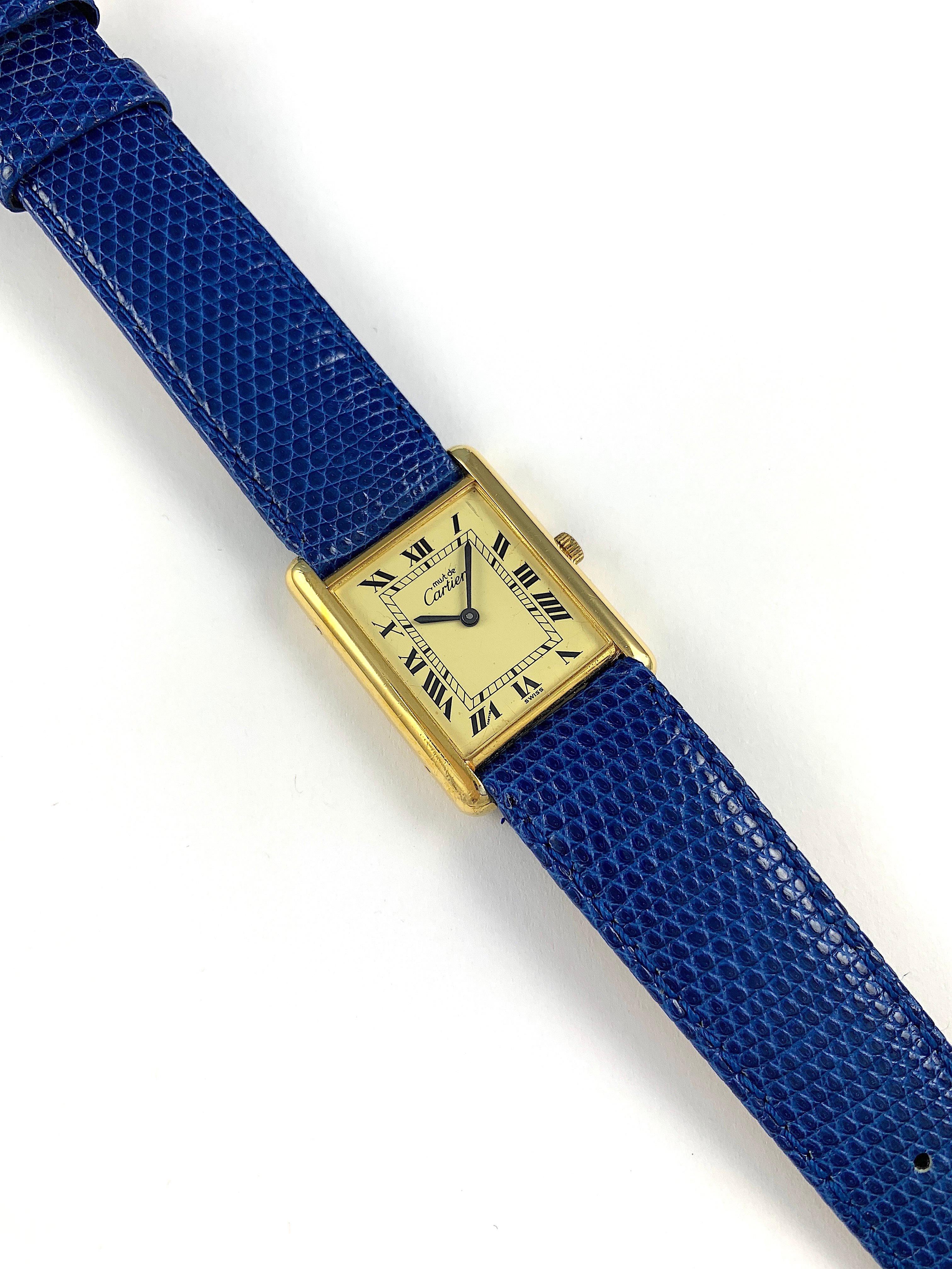 Must De Cartier Manual Wind Gold Plated Tank Watch
Champagne Dial with Black Roman Numerals and Matching Black Hands
Manual Wind Movement
Cartier Paris Must Argent Base Gold Electroplating
Signed and Engraved Case-Back
Generic Gold Toned Crown
Blue