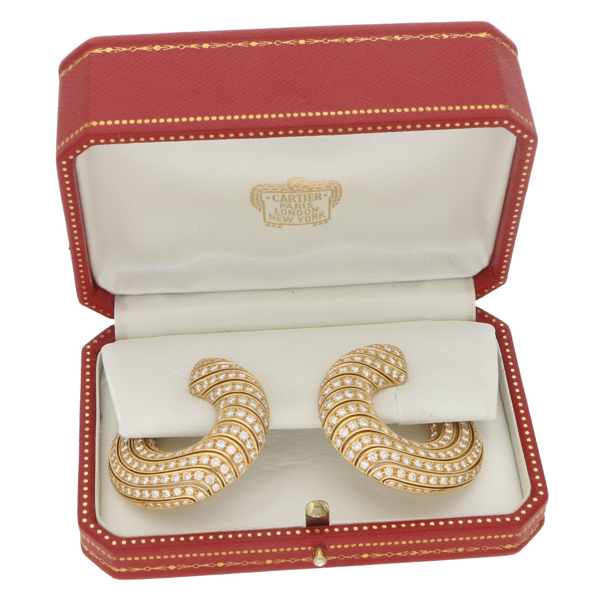 A rather beautiful pair of Cartier Neptune large vintage diamond side hoop earrings set in 18k yellow gold. 

Each earring is composed of 13 rows of waved round brilliant cut diamonds within a side hoop motif shape. Although a larger pair of hoops;