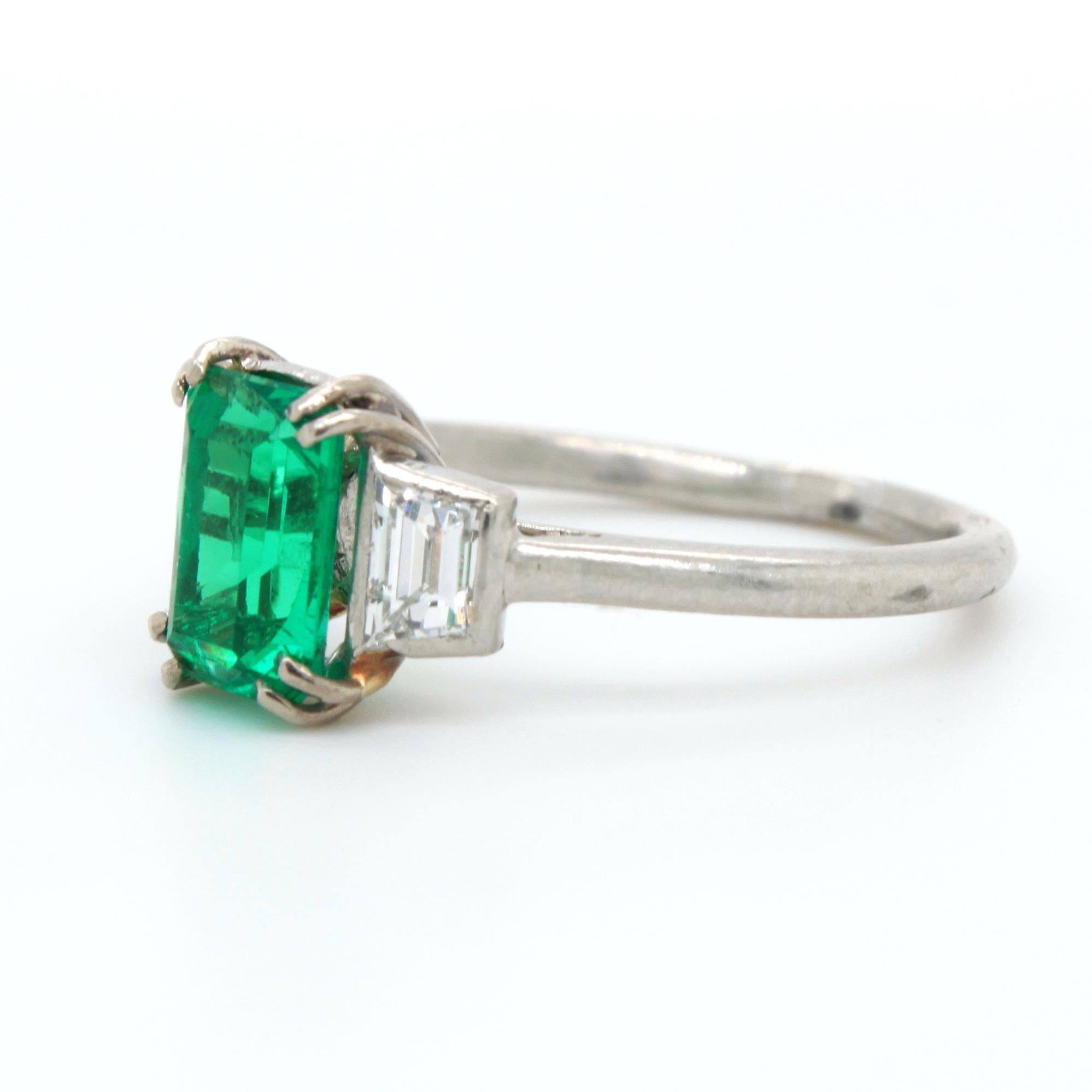 An exquisite emerald and diamond Art Deco ring in platinum by Cartier, France, ca. 1920s. 

The centre emerald is of exceptional quality. It has a vivid green colour, alluring crystal and is free of any eye visible inclusions. The emerald weighs