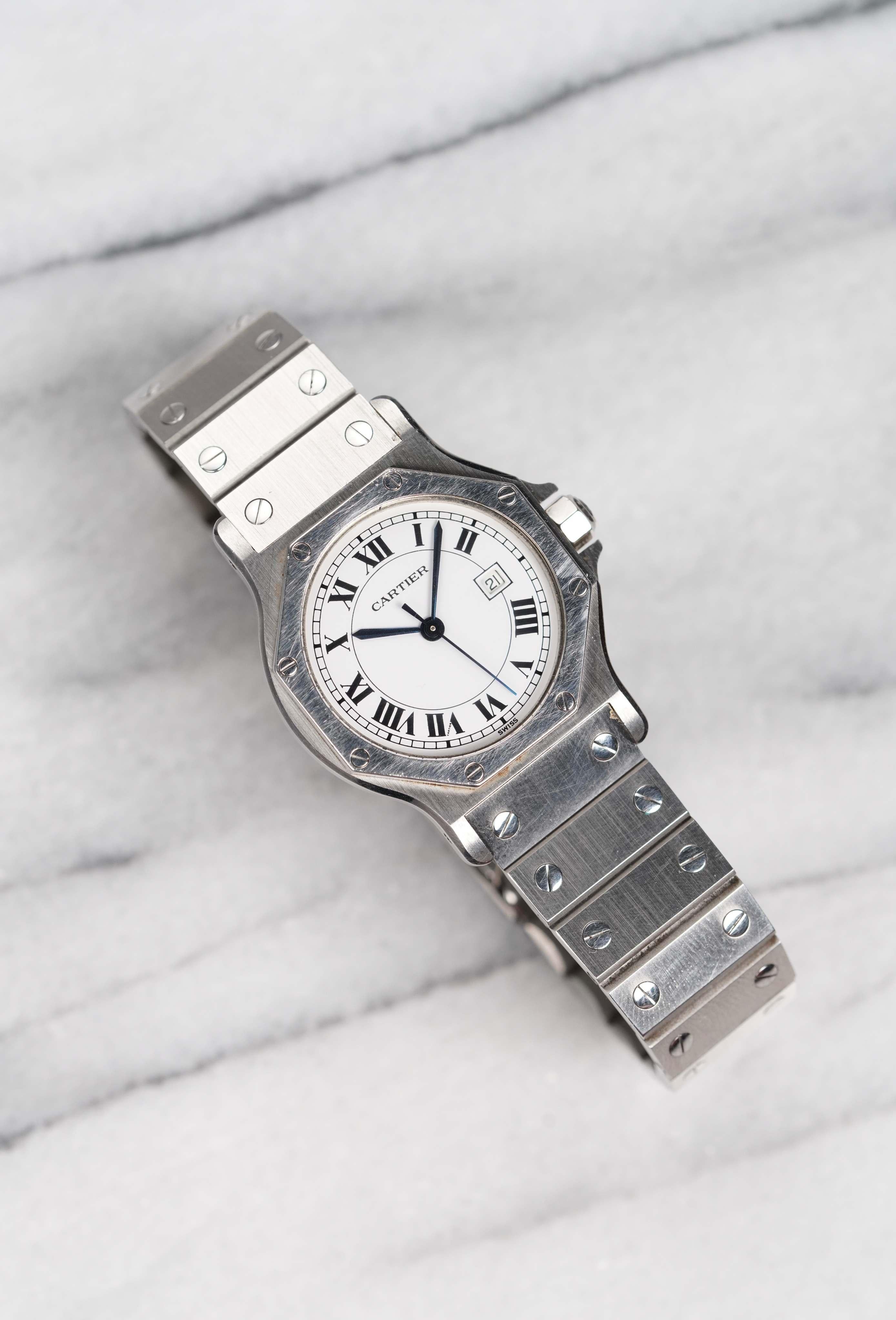 Aquí tienes un octógono automático Cartier vintage de referencia 2965 con esfera blanca de números romanos de finales de los 80, principios de los 90. Mantiene la hora y es totalmente funcional. Las medidas incluyen un tamaño de caja de 30 mm y una