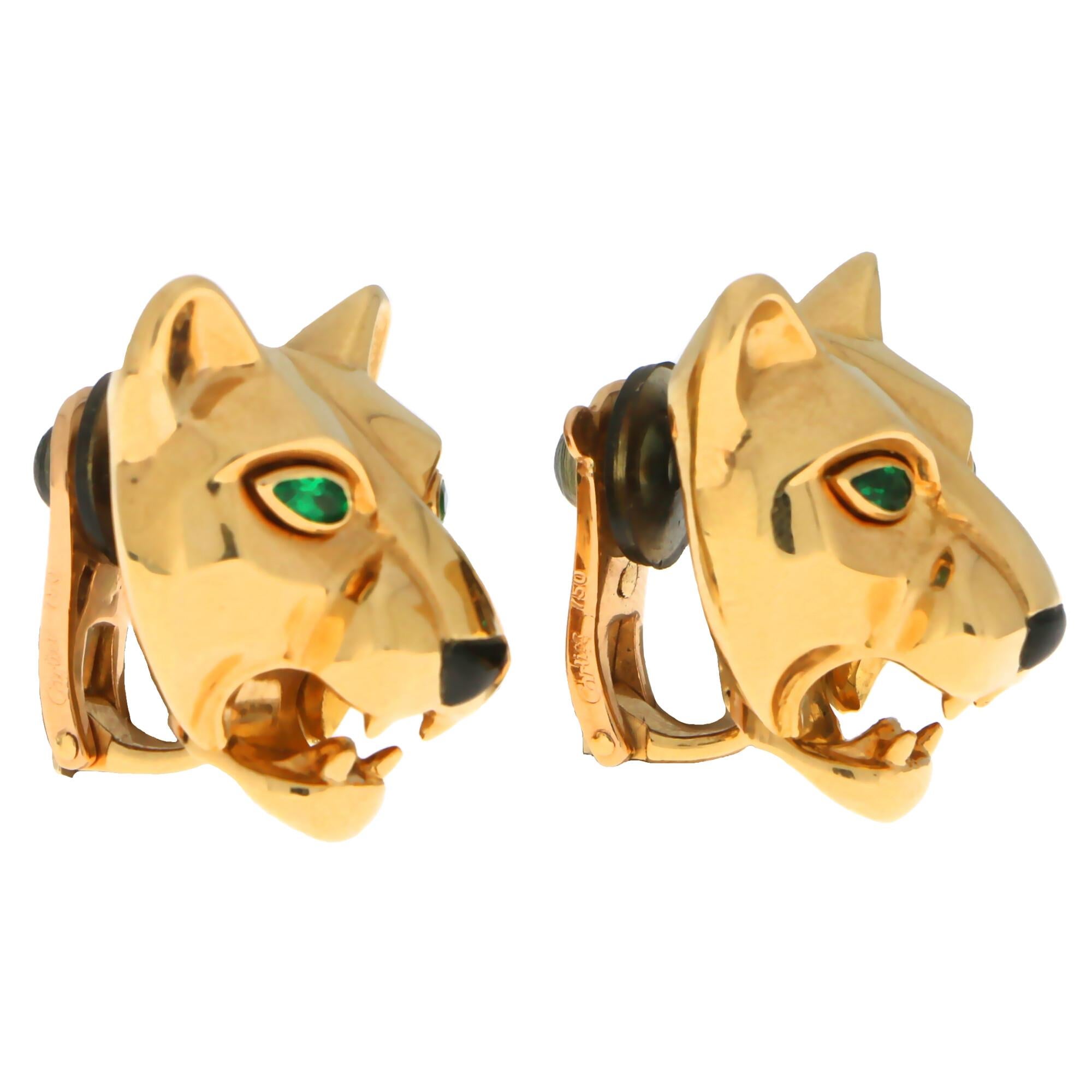 A striking pair of vintage Cartier emerald eyed panther clip on earrings made of 18k yellow gold.

Each earring depicts a beautifully detailed panther face which is set with two pear cut emerald eyes and a cute onyx nose. Unlike the more modern