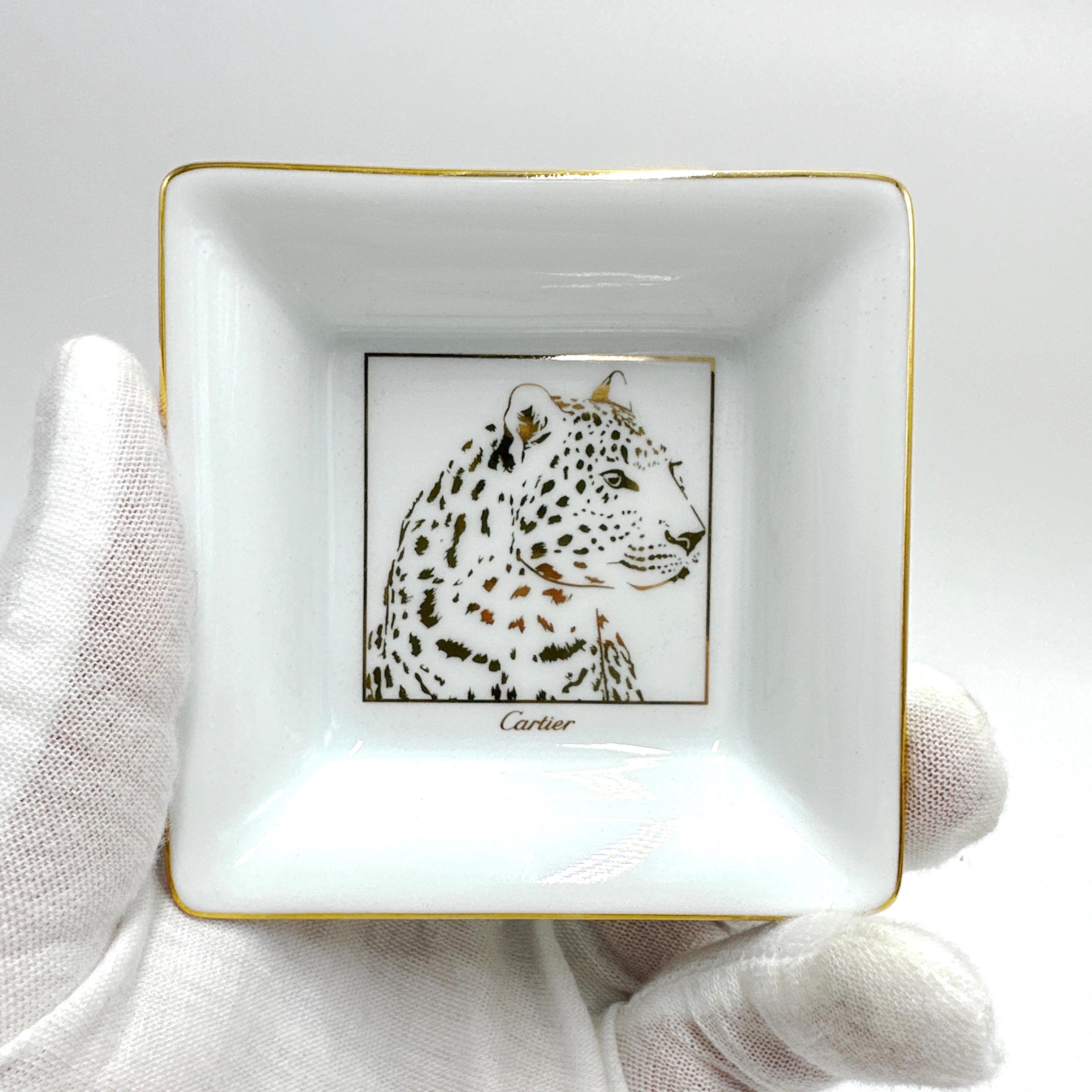 Here is a lovely CARTIER Panther Motif Porcelain Trinket Tray. This tray features a gold finish and showcases a beautiful Panther motif. Stamped Made in France on verso. 

These trays are typically given as gifts from Cartier for purchasing a more
