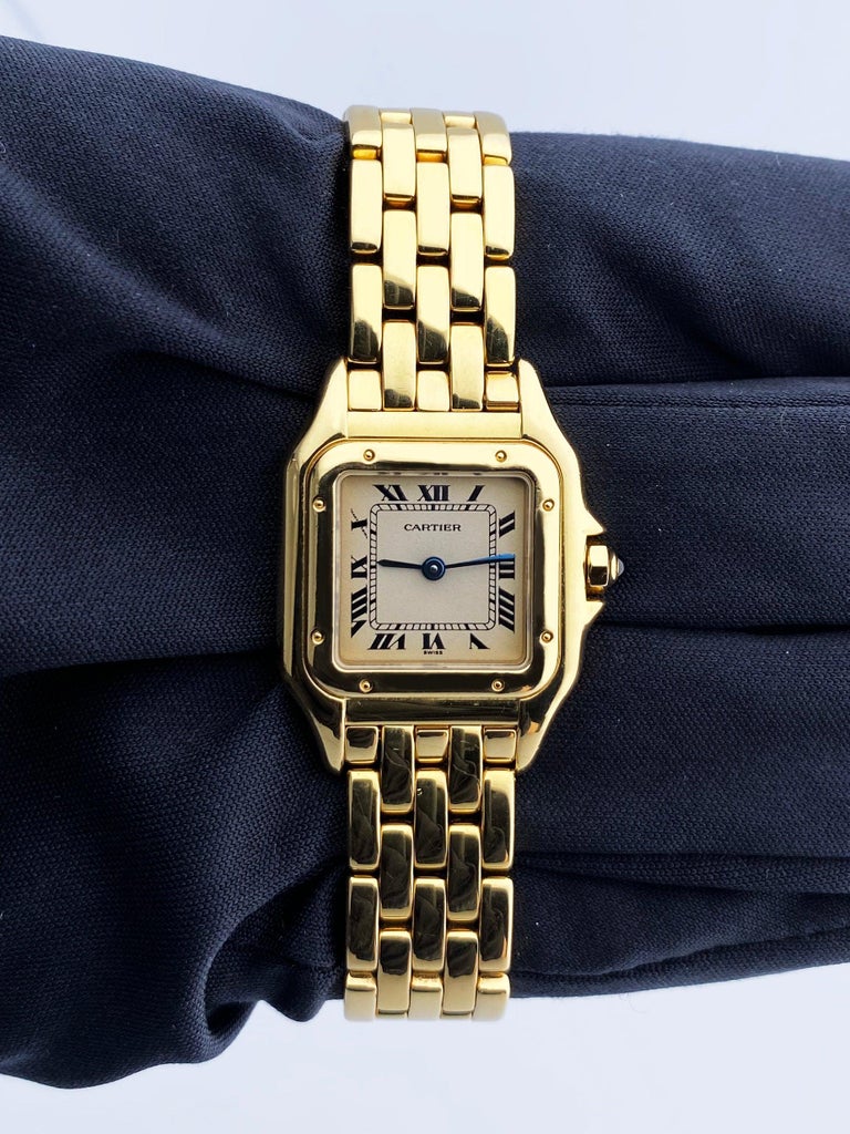 
Cartier Panthere Ladies Watch. 22mm 18K yellow gold case. 18K yellow gold smooth bezel. Off-White dial with blue steel hands and Roman numeral hour markers. Minute markers on the inner dial. 18K yellow gold bracelet with hidden butterfly clasp.