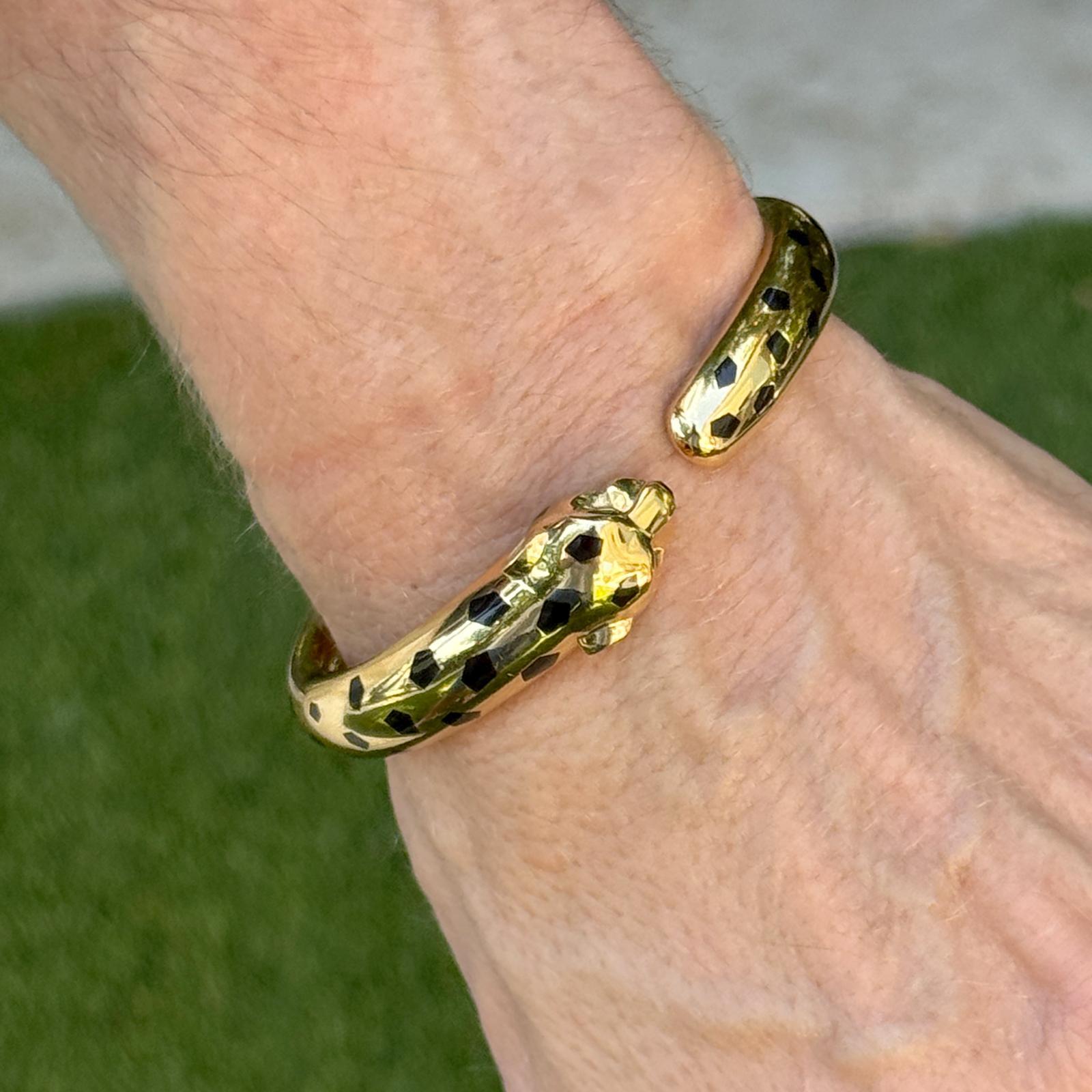 This Cartier Panthère de Cartier Bangle Bracelet is a luxurious piece from the iconic Panthère collection, crafted in 18K yellow gold. The design features Cartier's signature panther motif, with onyx and black lacquer accents, capturing the feline's