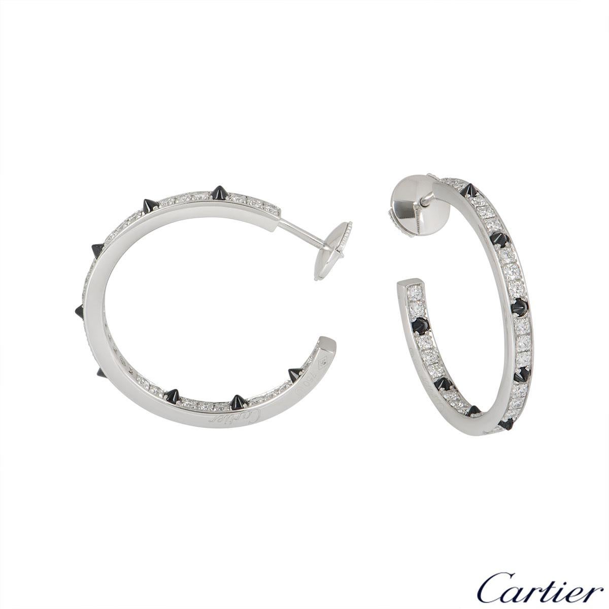 An 18k white gold pair of diamond and onyx earrings by Cartier from the Panthere De Cartier collection. The earrings are set with pave round brilliant cut diamonds and onyx spikes on either side of the hoops. The 52 diamonds have an approximate