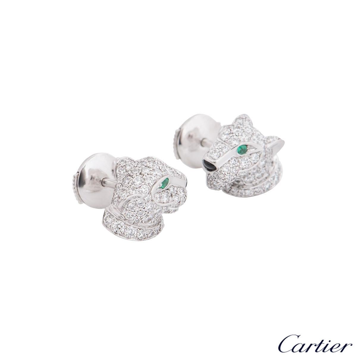An 18k white gold pair of diamond,emerald and onyx Cartier earrings from the Panthere De Cartier collection. The earrings feature a panther head set with 126 round brilliant cut diamonds in total with a weight of 0.76ct, round emerald eyes and onyx