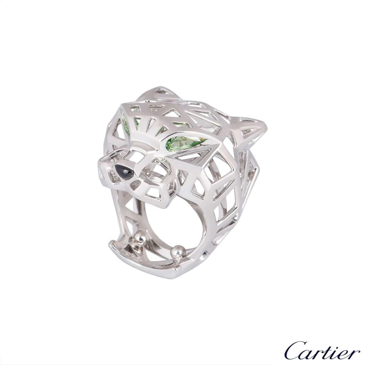 An exemplary 18k white gold Cartier dress ring from the Panthere De Cartier collection. The ring comprises of an open work panther motif with 2 pear cut tsavorite garnets featured as the eyes and an onyx nose. The ring was originally a size 53 (US