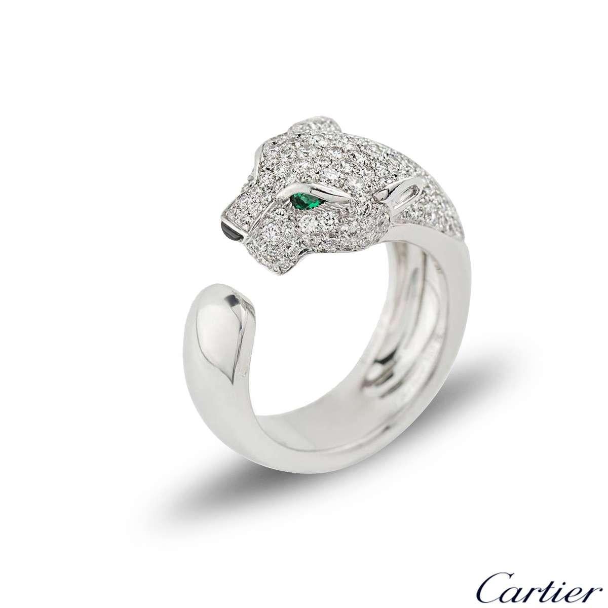A stunning 18k white gold Cartier diamond, onyx and emerald ring from the Panthere De Cartier collection. The ring is composed of a Panthere head motif, pave set with 137 round brilliant cut diamonds totalling 1.15ct, accentuated by two emeralds set