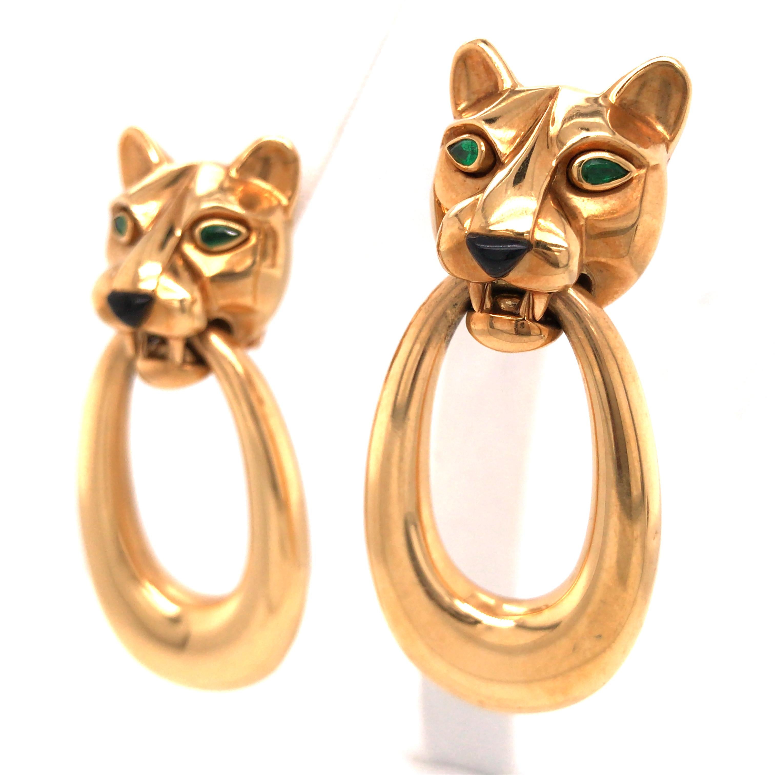 Cartier 18 Karat Yellow Gold Panthere Door Knocker Earrings.  Expertly set with (4) Pear Shape Emeralds and (2) Trillion shape Black Onyx Cabochons. The Earrings measure 2 1/8 inch in length and 7/8 inch in width.  Hoops are removable allowing the