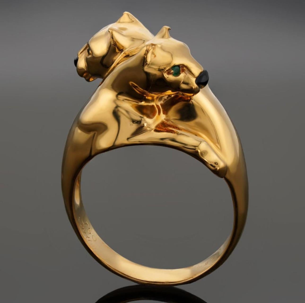 Iconic Panthère de Cartier ring, yellow gold 750/1000. It features an intertwined double panther head design accented with a black onyx nose and green emerald eyes.
Made in France, circa 1980

Signed Cartier 750, numbered, eagle and goldsmith head