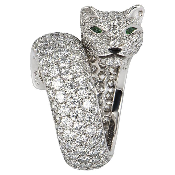 A stunning Cartier 18k white gold Lakarda Panthere diamond ring from the Panthere de Cartier collection. The wrap around style ring comprises of a panther motif with emerald eyes, an onyx nose and a diamond body. The ring features 308 round