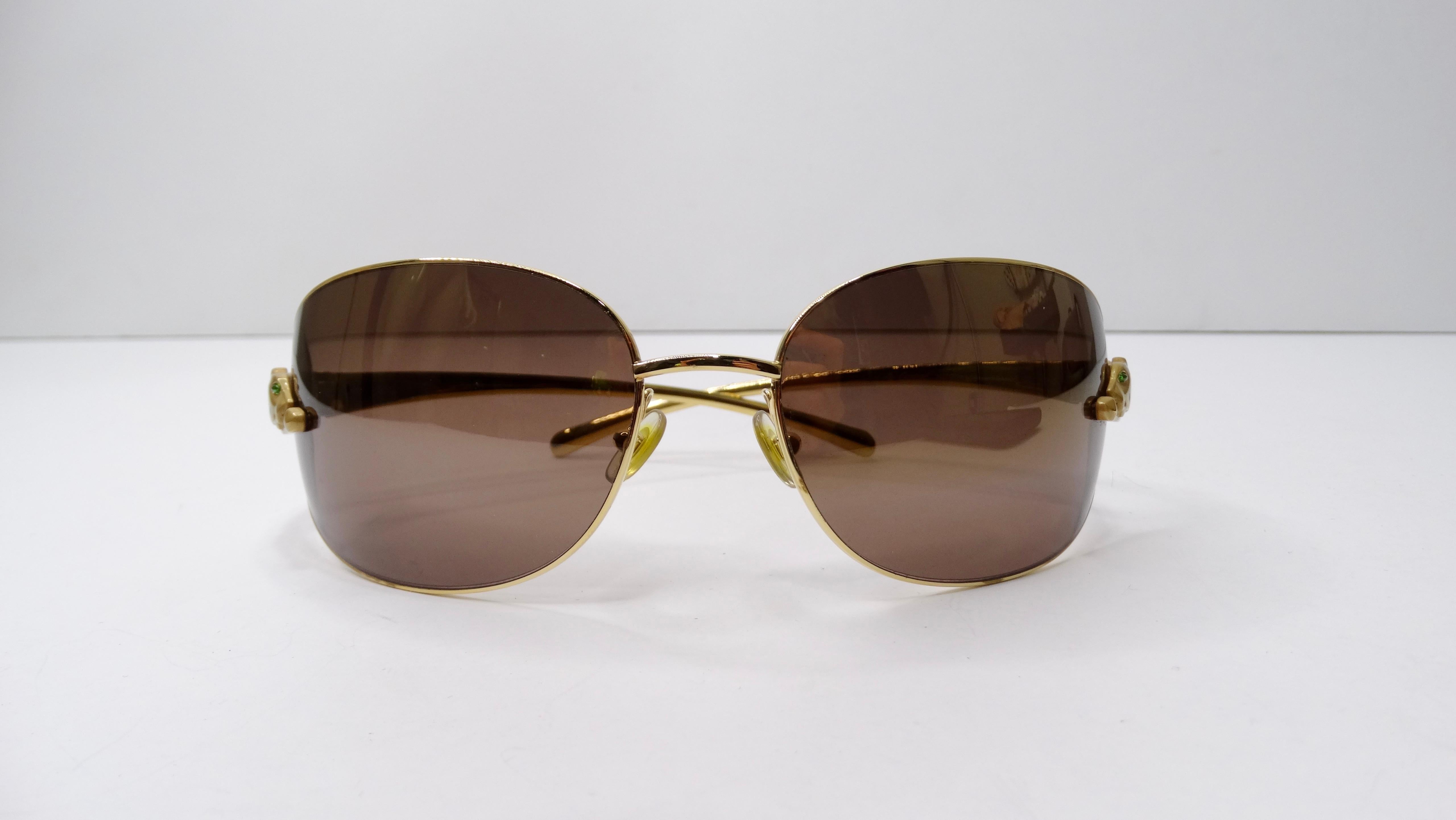 These limited series Panthere De Cartier 18k gold plated sunglasses feature burgundy brown lenses with a wrap style frame. The Cartier's distinctive panther logo in gold-plated metal with black enamel spots and emerald cabochon eyes adorn the