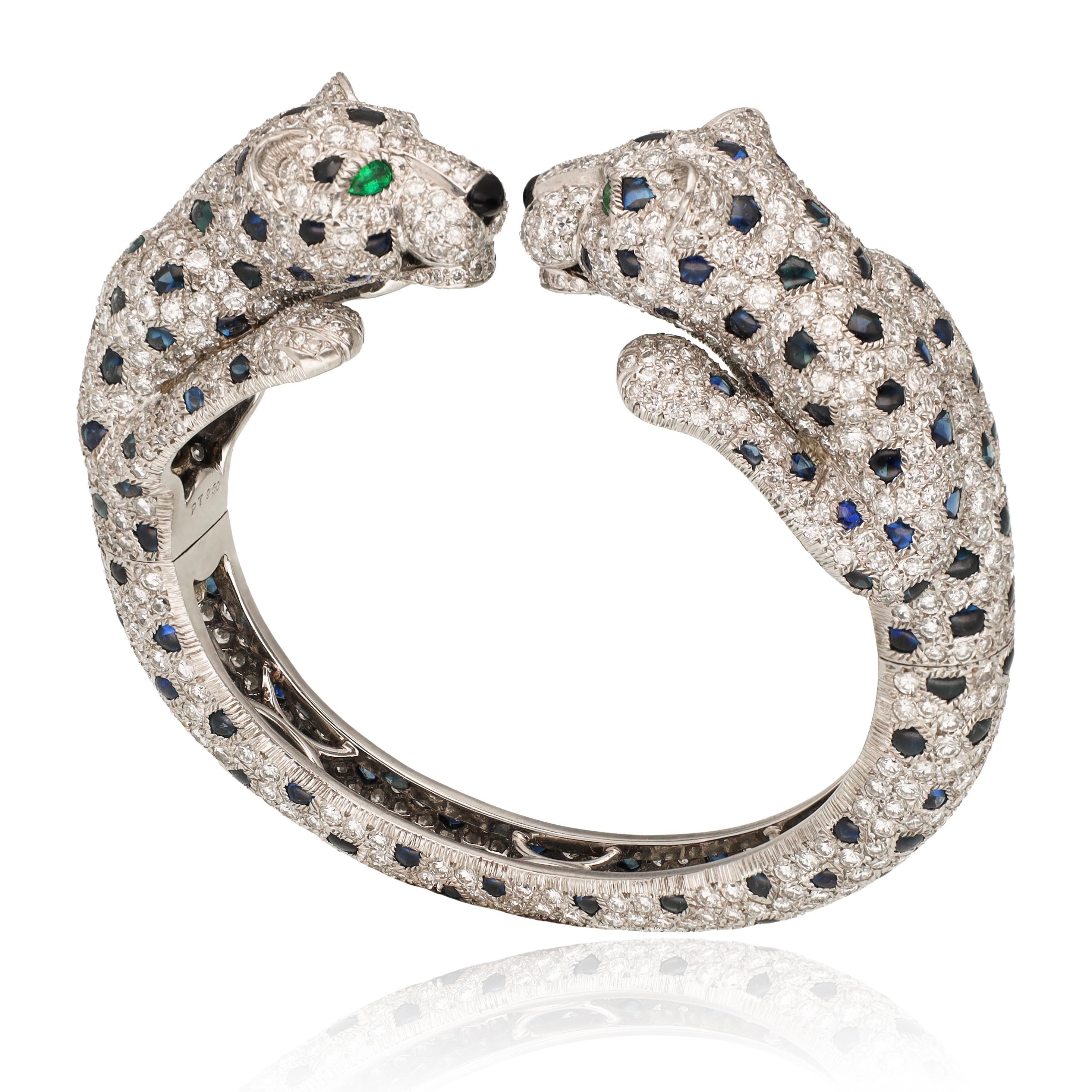 Ce bijou exquis présente un motif saisissant de deux panthères se faisant face, travaillé de manière experte pour capturer leur élégance féroce. Les panthères sont ornées de diamants taille brillant pavés qui brillent magnifiquement, chaque pierre