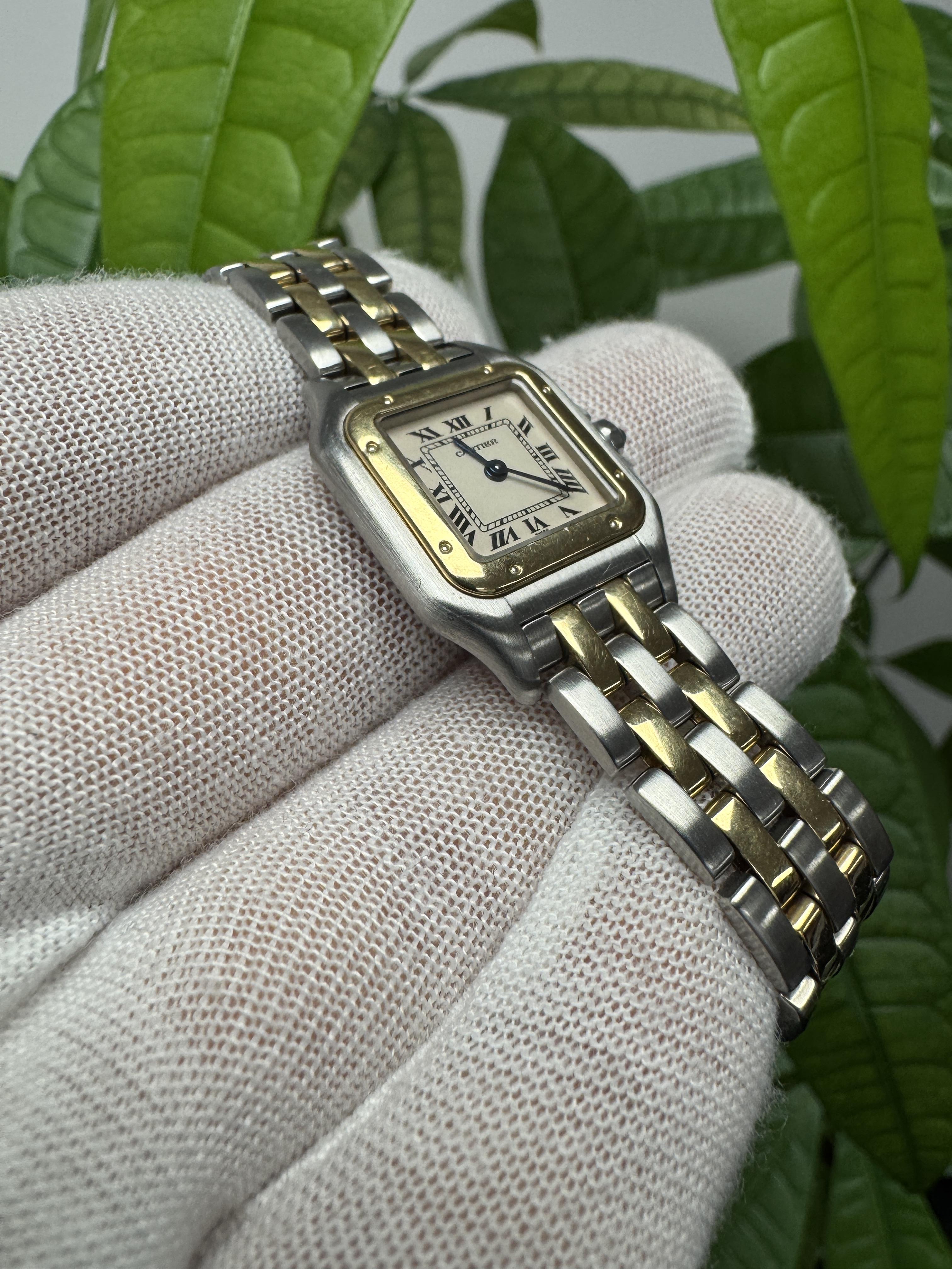 The Cartier Panthère small watch is an exquisite blend of sophistication and luxury. Its 22mm stainless steel case is complemented by an 18K yellow gold bezel, creating a stunning visual appeal. The ivory dial features elegant blue steel hands and