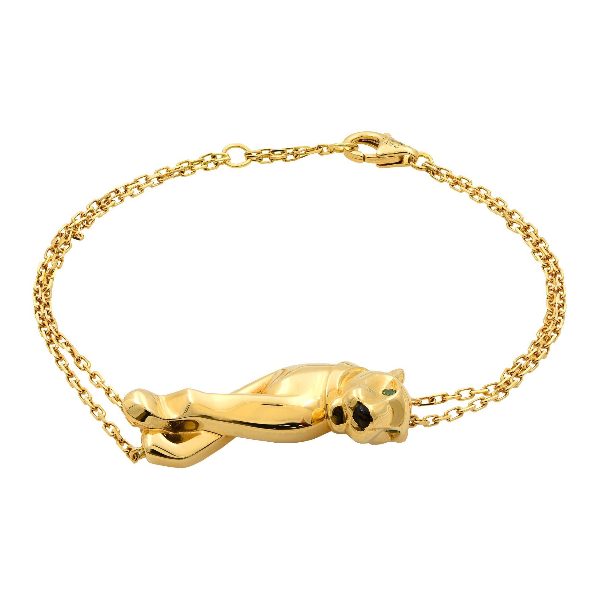 Panther Bracelet by Cartier crafted in 18k Yellow Gold Featuring Solid Gold Panther Centerpiece.The panther head is enhanced with black lacquer detailing and set with gorgeous tsavorite garnet for the eyes. The bracelet is held by double chains that