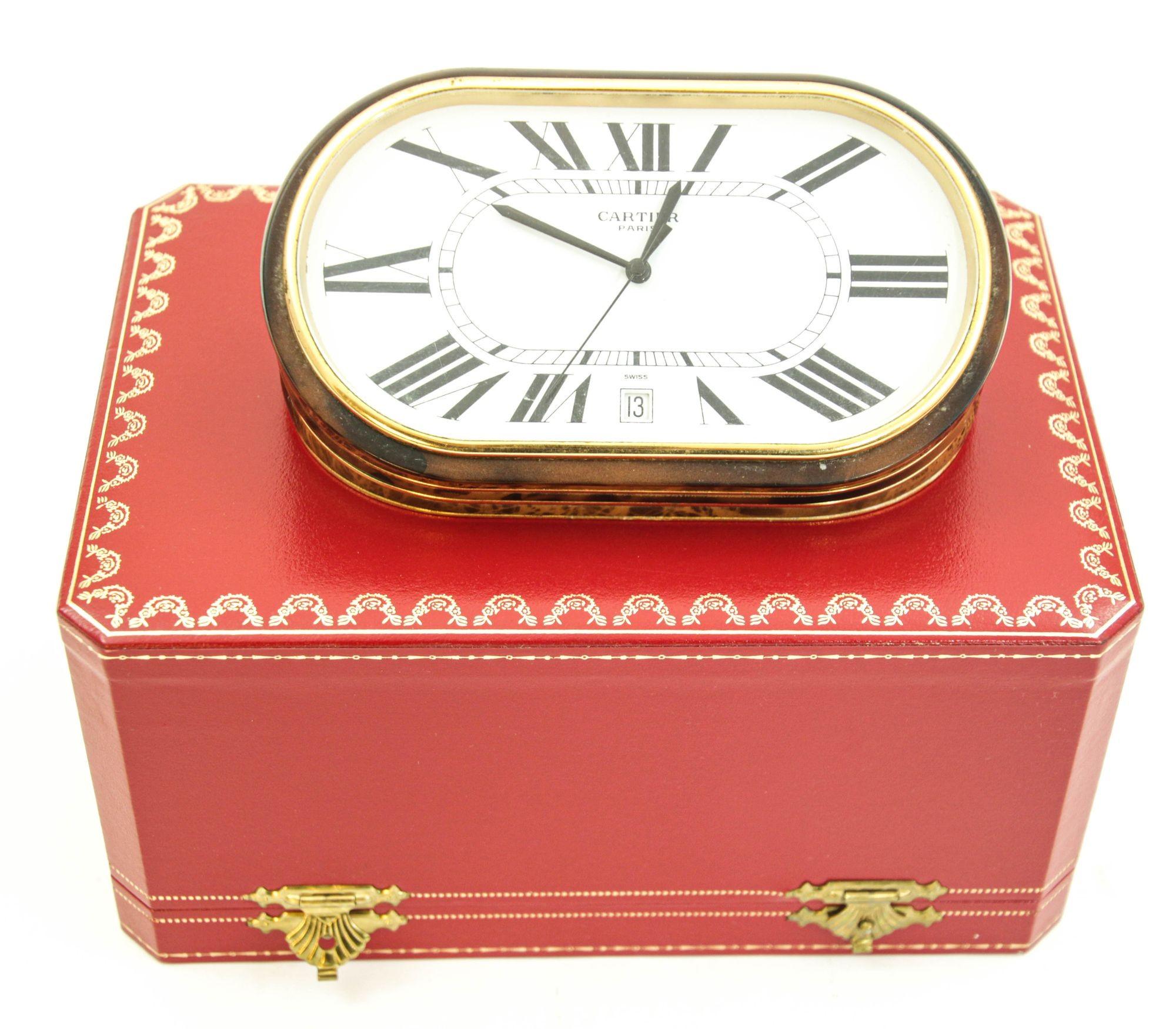Reloj acordeón Cartier París con fecha y esfera blanca de números romanos.
Movimiento de cuarzo Art Déco con esmalte marrón burlwood Modelo Accordion grande de Cartier, metal de base dorado.
Reloj de sobremesa pesado vintage de acordeón ovalado Les
