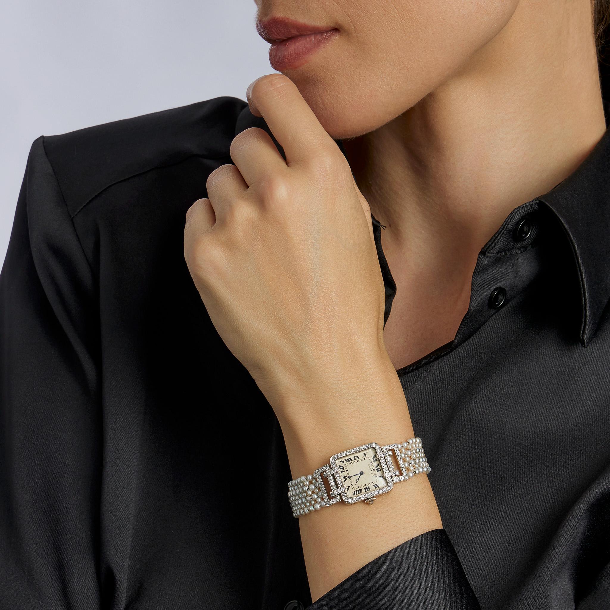 Diese frühe Armbanduhr aus Platin, Saatperlen und Diamanten stammt aus den 1910er Jahren und wurde von Cartier Paris in Zusammenarbeit mit Edmond Jaeger und European Watch & Clock entwickelt. Das quadratische Gehäuse mit abgerundeten Ecken, markiert
