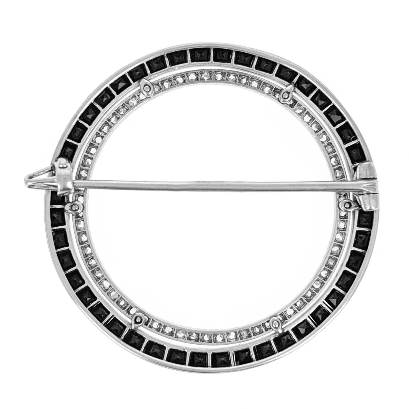 This Art Deco circle brooch by Cartier Paris features a row of rose cut diamonds further encircled by a row of calibre cut onyx. It is expertly crafted in platinum with milgrain detailing. Signed and numbered. Measures approximately 1.38 inches in