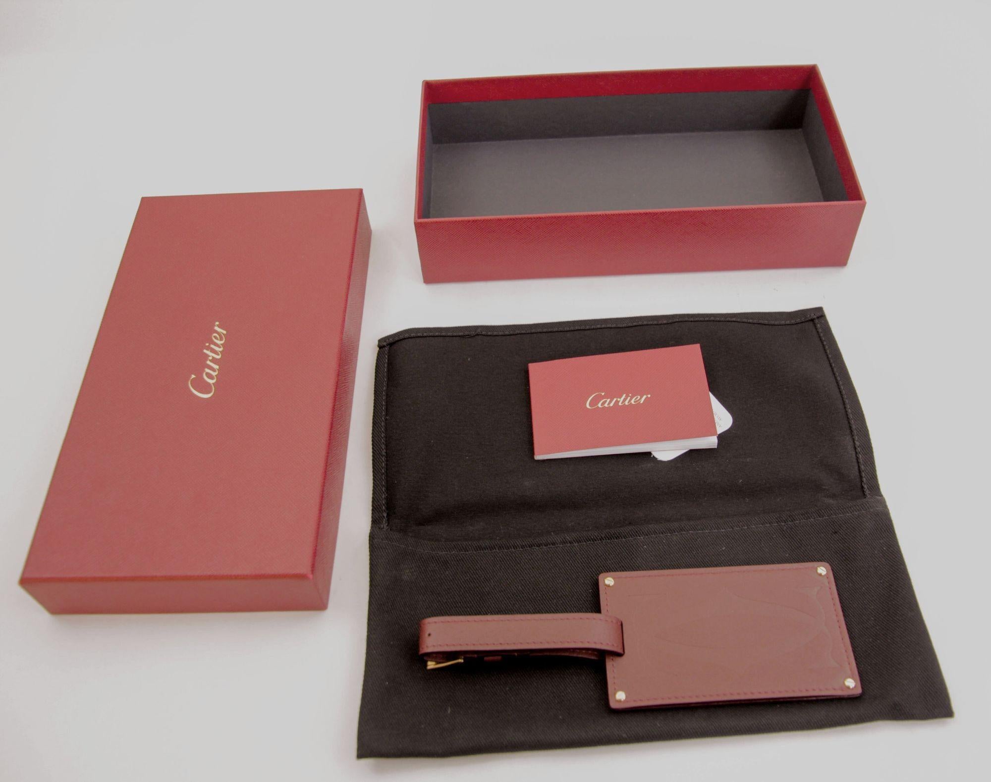 The Cartier Paris burgundy calfskin leather luggage tag is as stylish as it is practical with gold-finished metal corners and embossed double C logo.
The luxury Cartier brand luggage tag attached to a bordeaux leather strap.
Iconic figural 