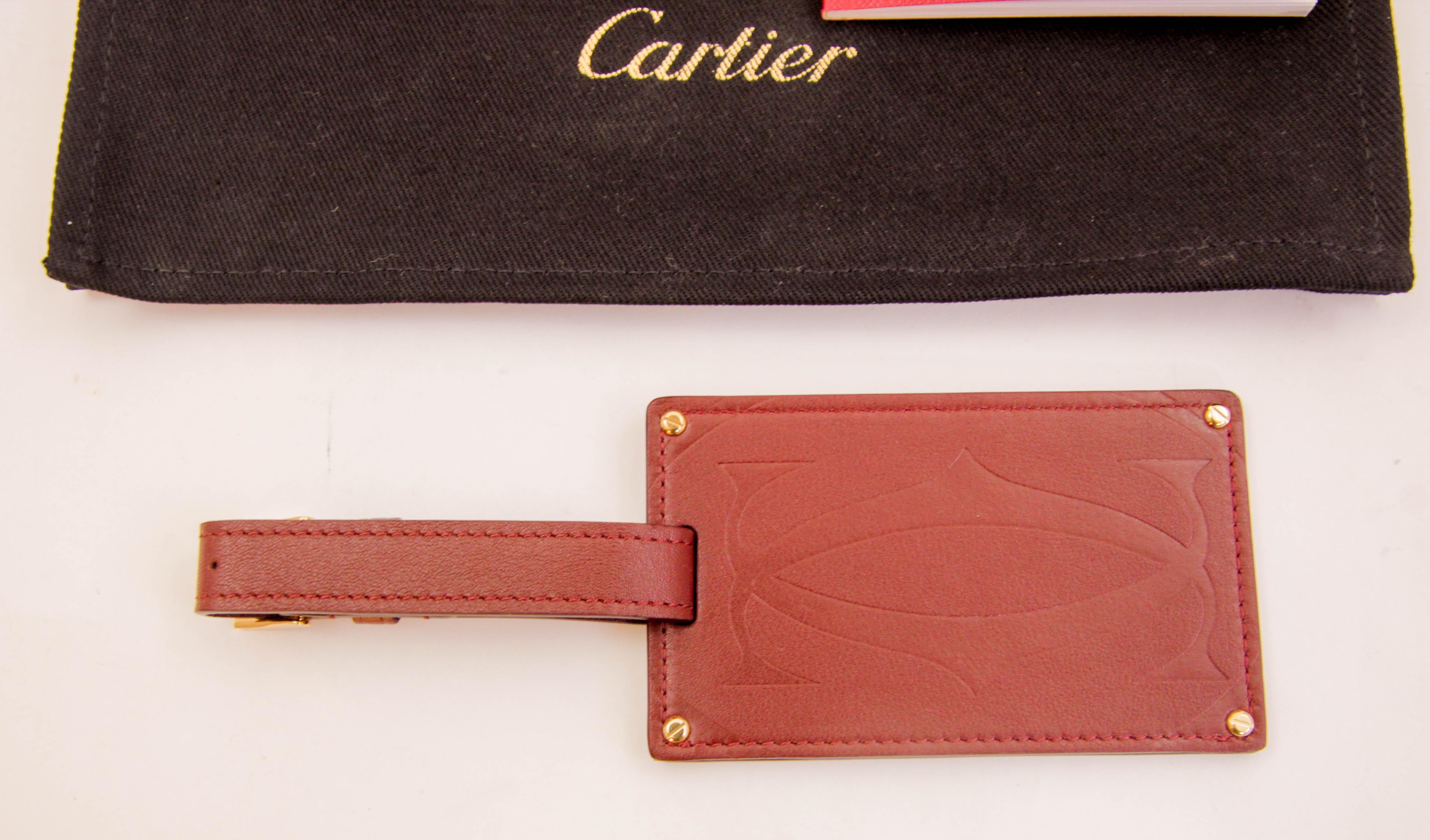 This Cartier Paris burgundy calfskin leather luggage tag is as stylish as it is practical with gold-finished metal corners and embossed double C logo.
The luxury Cartier brand luggage tag attached to a bordeaux leather strap and brass gold metal
