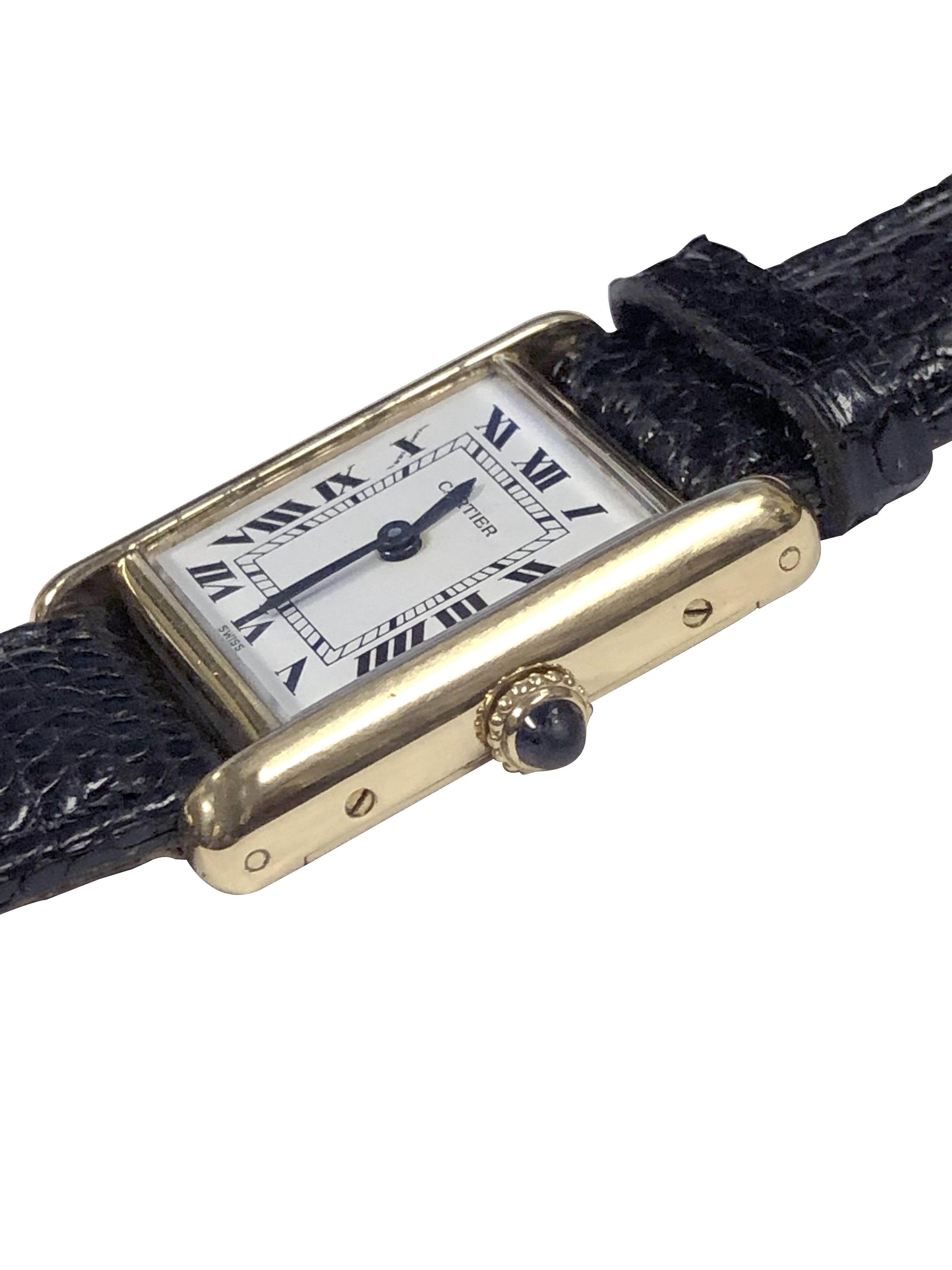 Circa 1990 Cartier Paris Ladies Classic Tank Wrist Watch, 20 X 19 M.M 18K Yellow Gold 2 piece case. Mechanical, manual wind movement, Sapphire crown, White dial with Black Roman Numerals. New Black Lizard Strap. Watch Length 7 1/4 inches. Comes in a