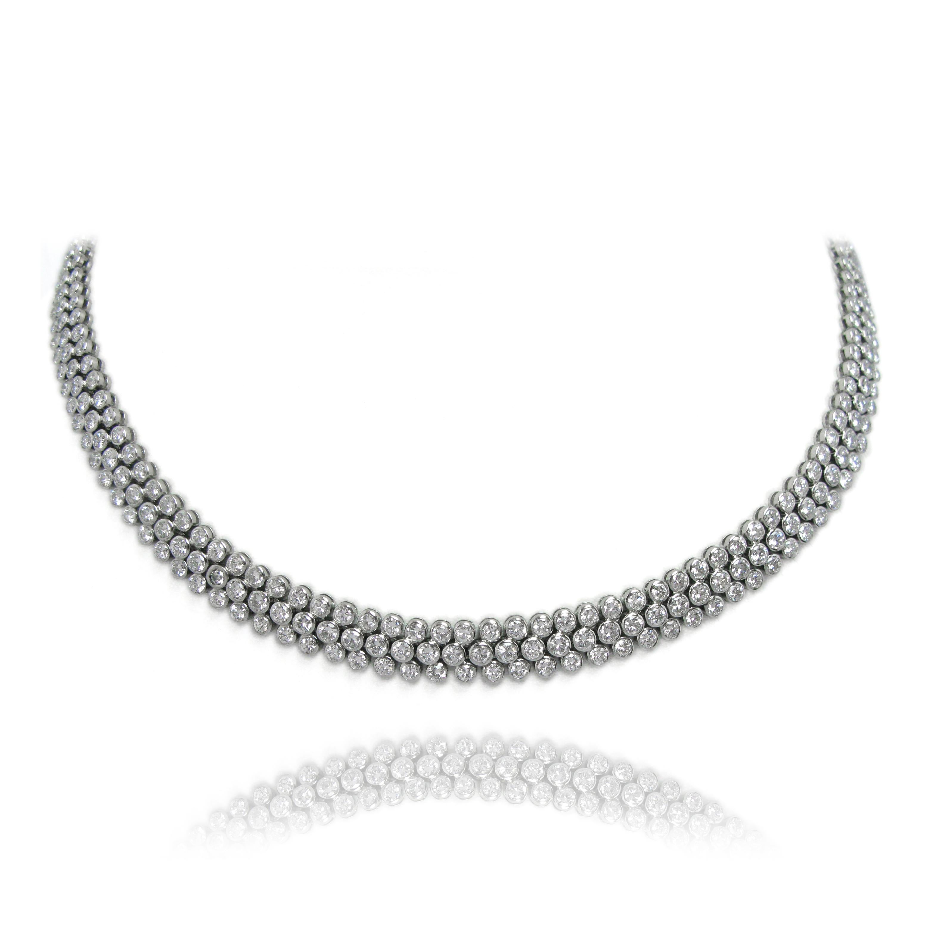 This stunning, vintage, platinum necklace is set with 19.56 ctw of round brilliant-cut diamonds, bezel-set in triple-line flexible links. Clasp stamped 