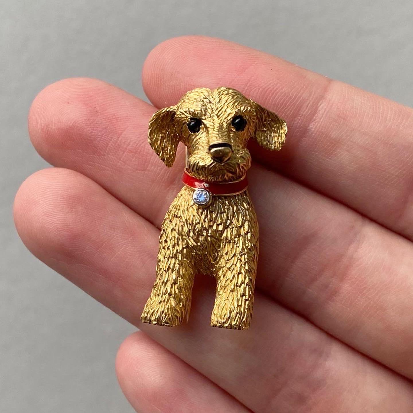 A super cute 18 carat yellow gold Cartier puppy brooch with a 
red enamel collar set with a small diamond (app. 0.04 carat). The eyes are 
made of onyx. Signed Cartier Paris and numbered 018187. Hallmark of the 
goldsmith. In the original Cartier