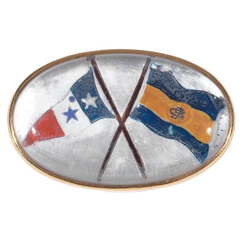 With a domed oval rock crystal reverse intaglio painted to depict two multicolored enamels yacht club navy flag

Mounted in 18Kt yellow gold

Signed Cartier Paris and numbered 3540C, French Gold Mark

Measurements: 33 x 21 mm

Gross weight: 12.3 gr

