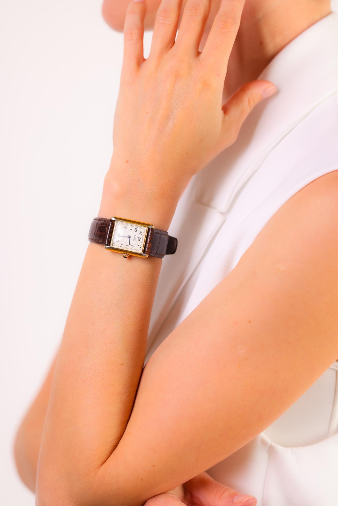This vintage Cartier Paris Tank watch exudes timeless elegance with its gold-plated case, brown leather strap, and precise quartz movement.

Brand: Cartier Paris
Movement: Quartz
Metal: Gold plated silver watch and brown leather strap
Era: