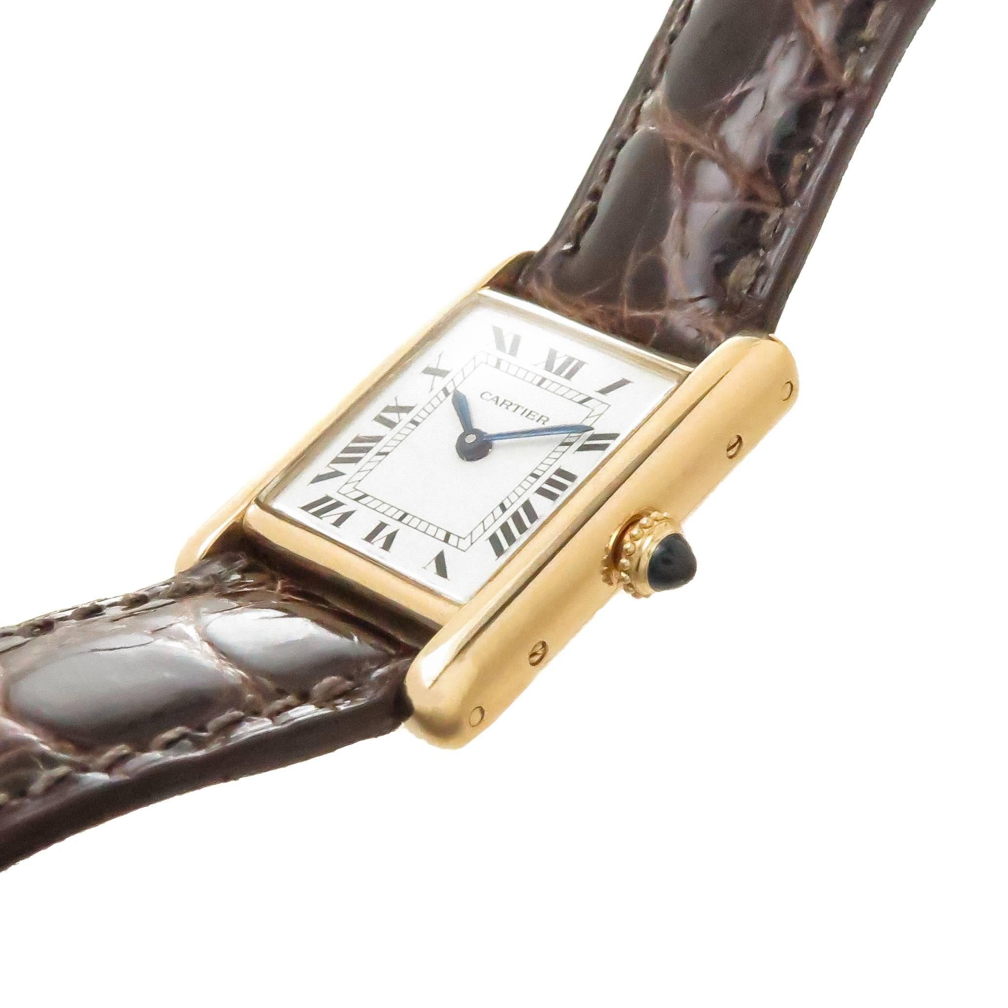 Circa 1980s Cartier Paris Classic ladies Tank Wrist watch,  28 X 20 MM 18K Yellow Gold 2 Piece Case. 17 Jewel Cartier Mechanical, Manual wind movement. White Dial with Black Roman numerals. New Brown Alligator Strap with Cartier Gold Plate Tang