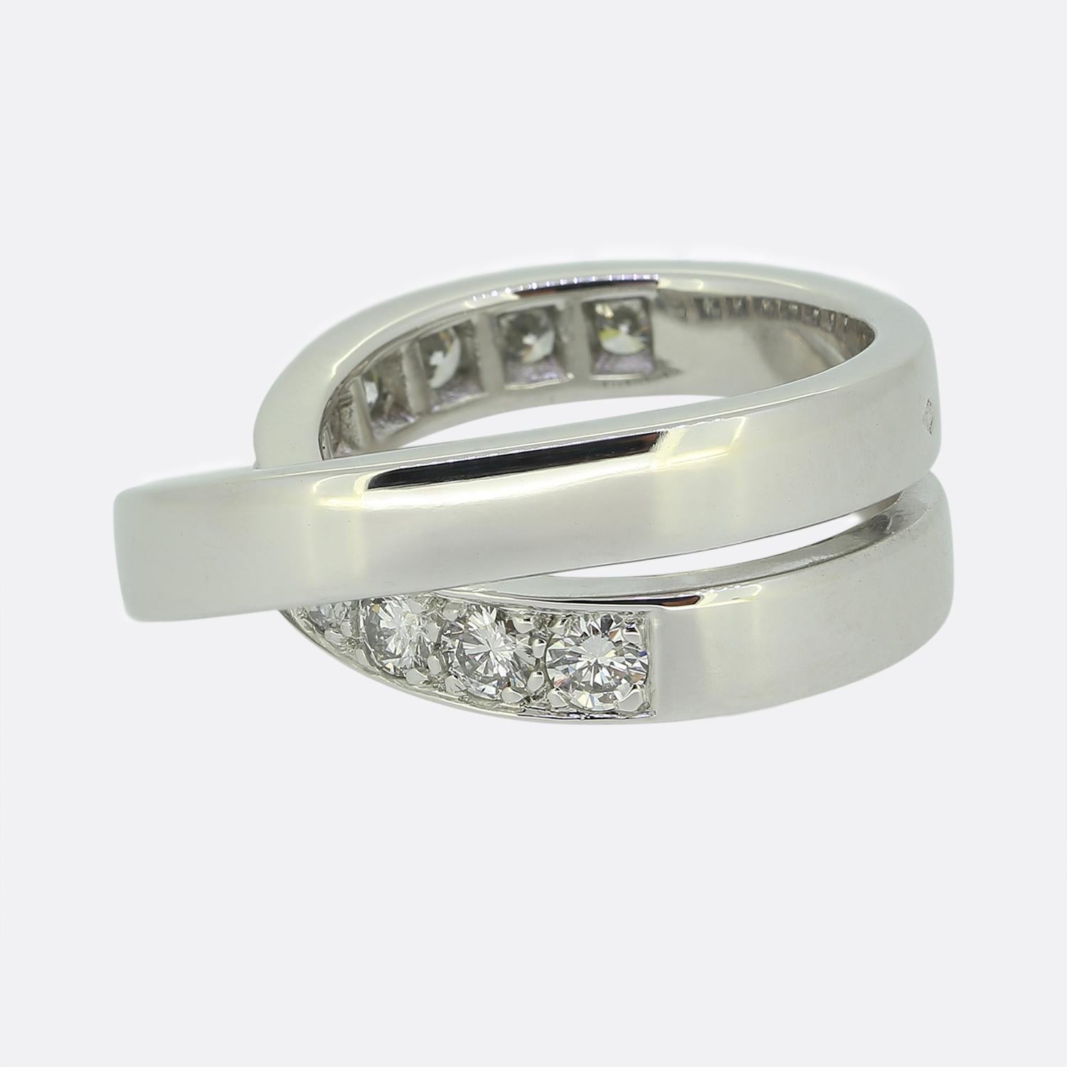Ecco un favoloso anello di diamanti Paris Nouvelle Vague della famosa casa di gioielli di lusso Cartier. Questo elegante e classico design incrociato è composto da due fasce intrecciate, una delle quali è stata incastonata con undici diamanti