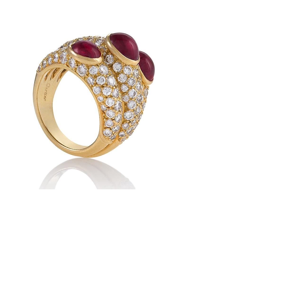 Cette bague glamour à trois anneaux en rubis et diamants présente le style et le savoir-faire incomparables de Cartier. Serti de diamants pavés étincelants, le triplet de rubis cabochons d'une superbe couleur forme une ligne diagonale à travers