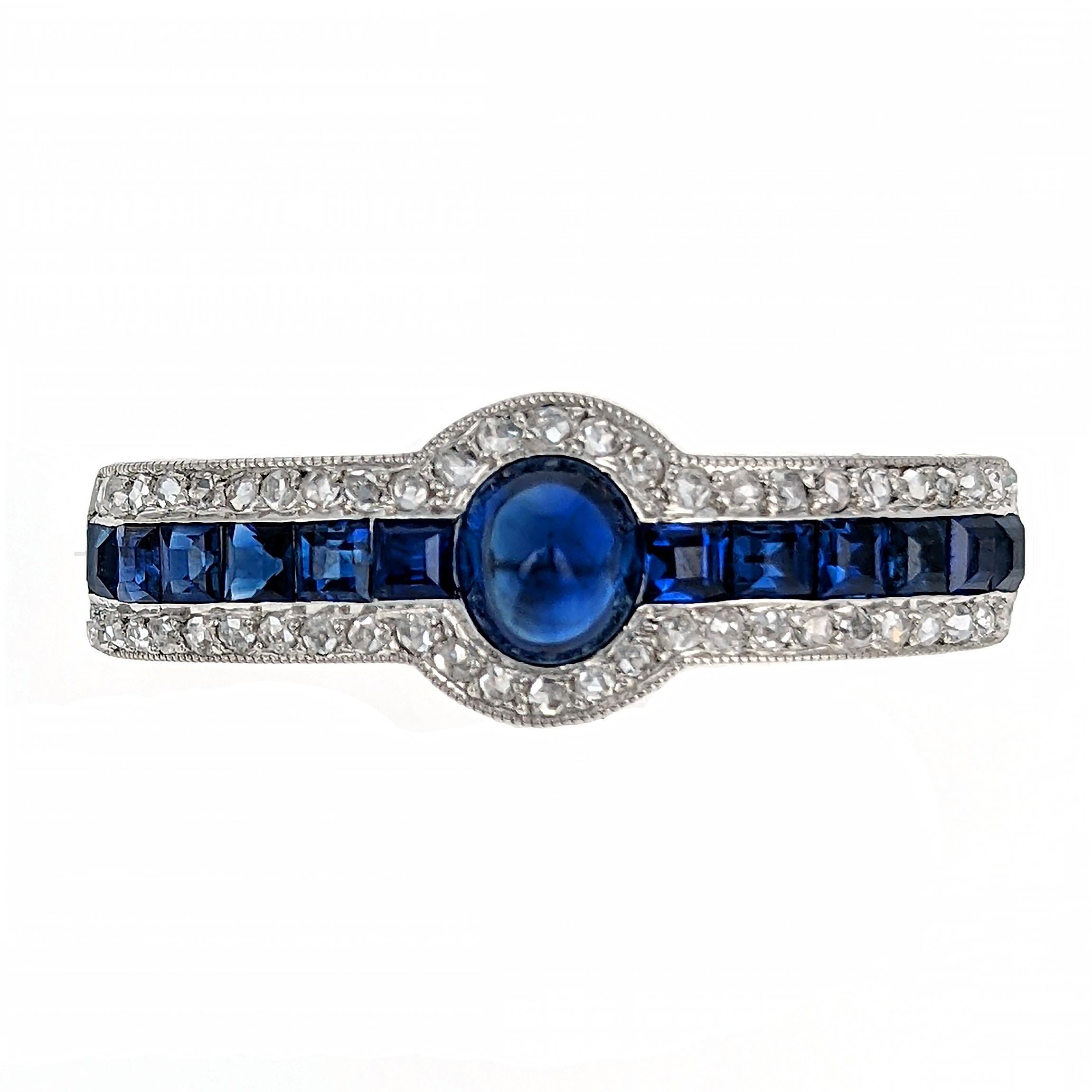 This stunning and elegant rounded brooch centers upon a row of calibré-cut sapphires flanking a single cabochon sapphire. It is edged with old rose-cut diamonds and mounted in millegrain set platinum. It is signed Cartier Paris with illegible serial
