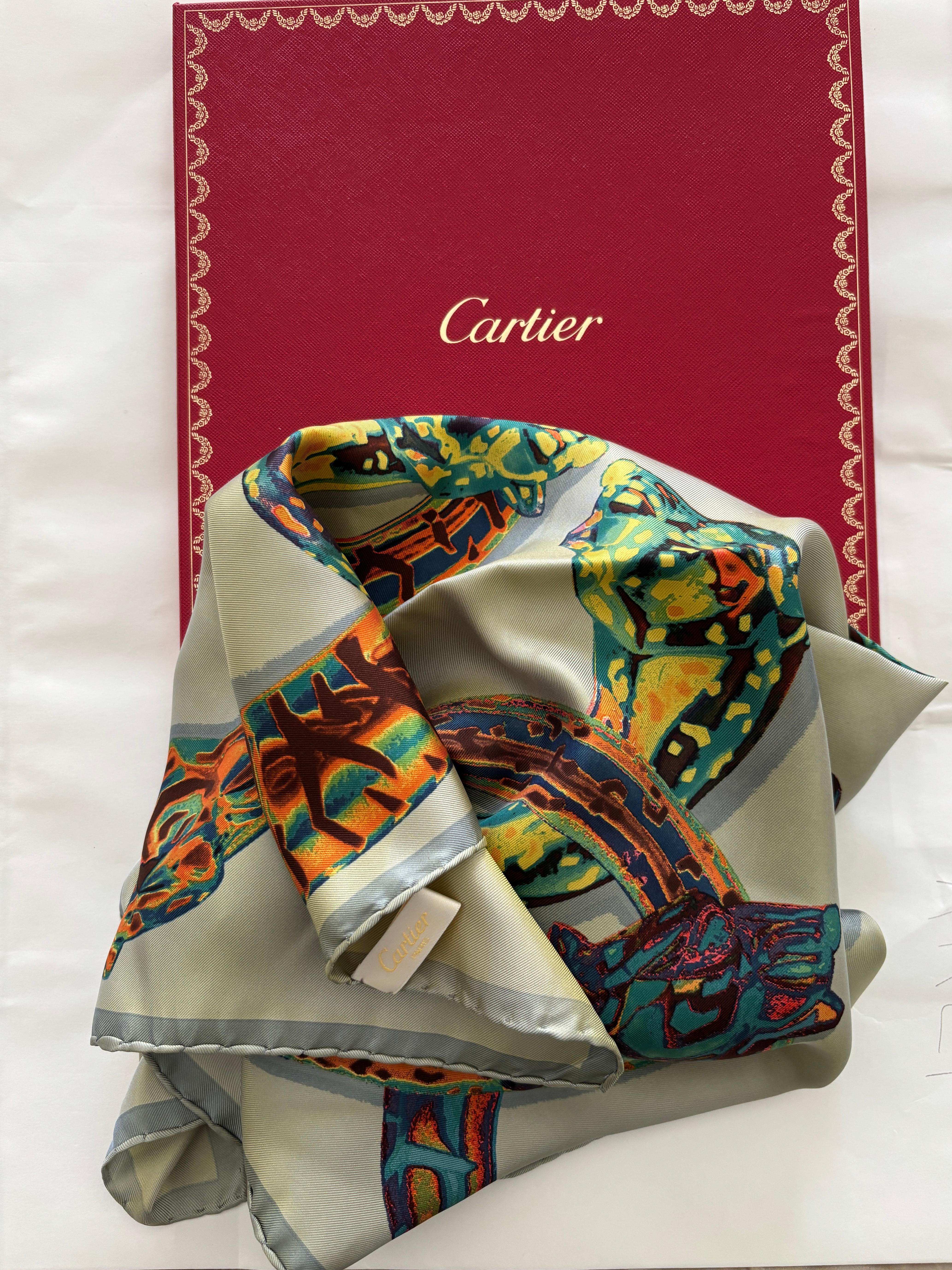 CARTIER Paris in Box Elegant Silk Scarf .
Blue border with a gold yellow and orange background with feline and sensual grace  the legendary bracelets by Cartier. 
The Cartier Silk Print Scarf is a stunning piece that pays homage to intricate