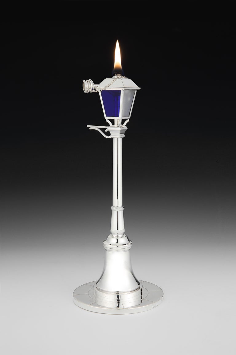 Cartier, Paris

A remarkable and most likely unique Sterling silver table lighter in the form of a 1930s gas street lamp. The tapering lantern reflector with blue and frosted glass panes, holds the wick which is revealed by removing the chained