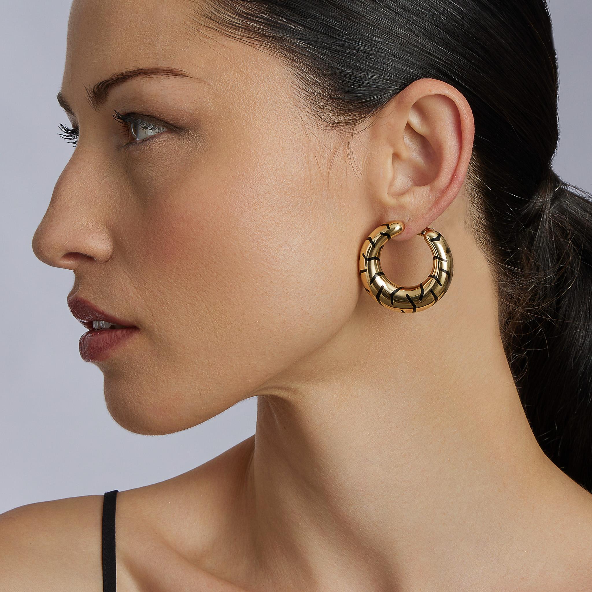 Created by Cartier Paris in the early 21st century, these hoop earrings are composed of black enamel and 18K gold. Each 18K gold hoop earclip is designed with irregular black enamel tiger stripes, and angled to sit snugly by the ear and face. Casual