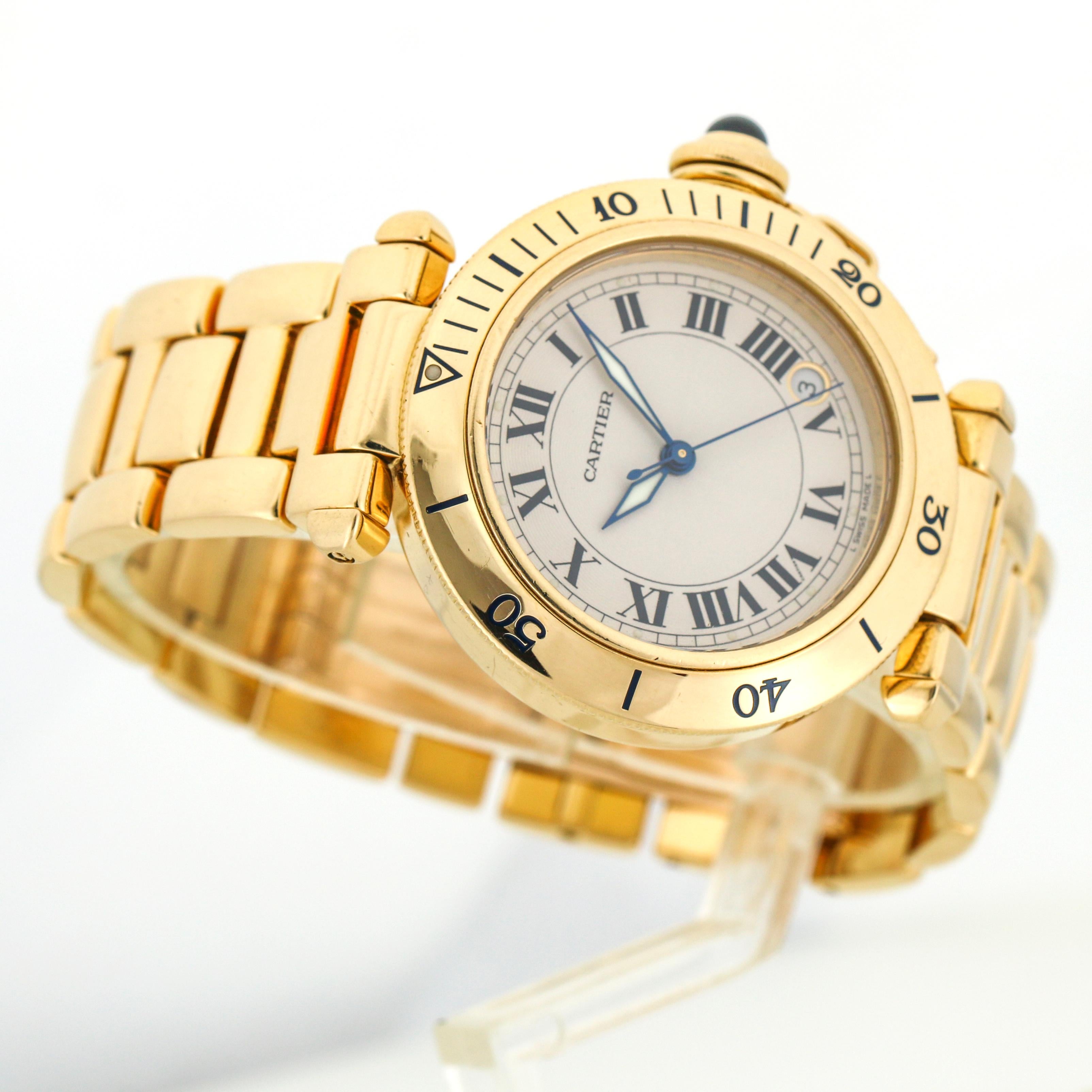 Cartier Pasha 1035 watch in 18-karat yellow gold. Polished metal case and bracelet. White dial with black Roman numeral hour marker's and Cartier's signature luminescent sword hands. Date window between 4 and 5 o'clock positions. Screw crown. Double