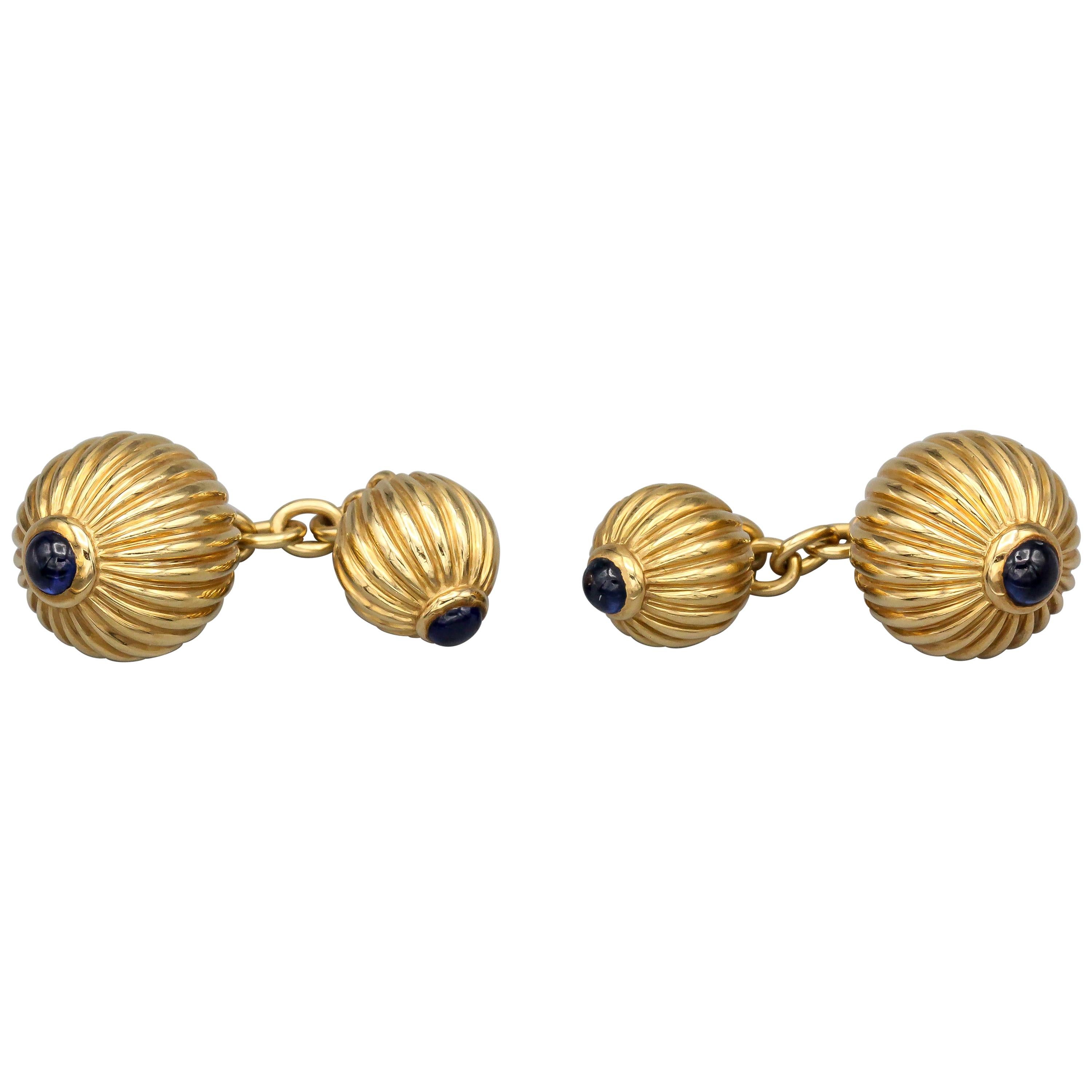 Rare and fine cabochon sapphire and 18K yellow gold cufflink and three stud set,  from the Pasha collection by Cartier, circa 1991. They feature a round, ribbed designs with cabochon sapphire ends .

Hallmarks: Cartier, 1991, reference numbers, 750.