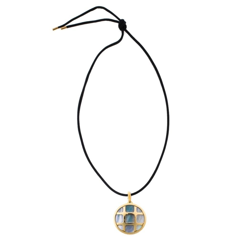 Don luxury with this beautiful necklace from Cartier's Pasha de Cartier collection. It has a round-shaped pendant made from 18K yellow gold with mother of pearl inlay and a cage-like design. A black cord, accented with metal tips, completes the