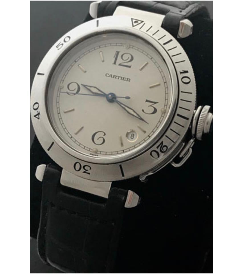 Classy pre-owned stainless steel Cartier Pasha. The watch features an off-white dial with black numerals and sword style hour and minute hands. This watch features a rotating bezel sitting atop the all stainless steel case construction. Powered by